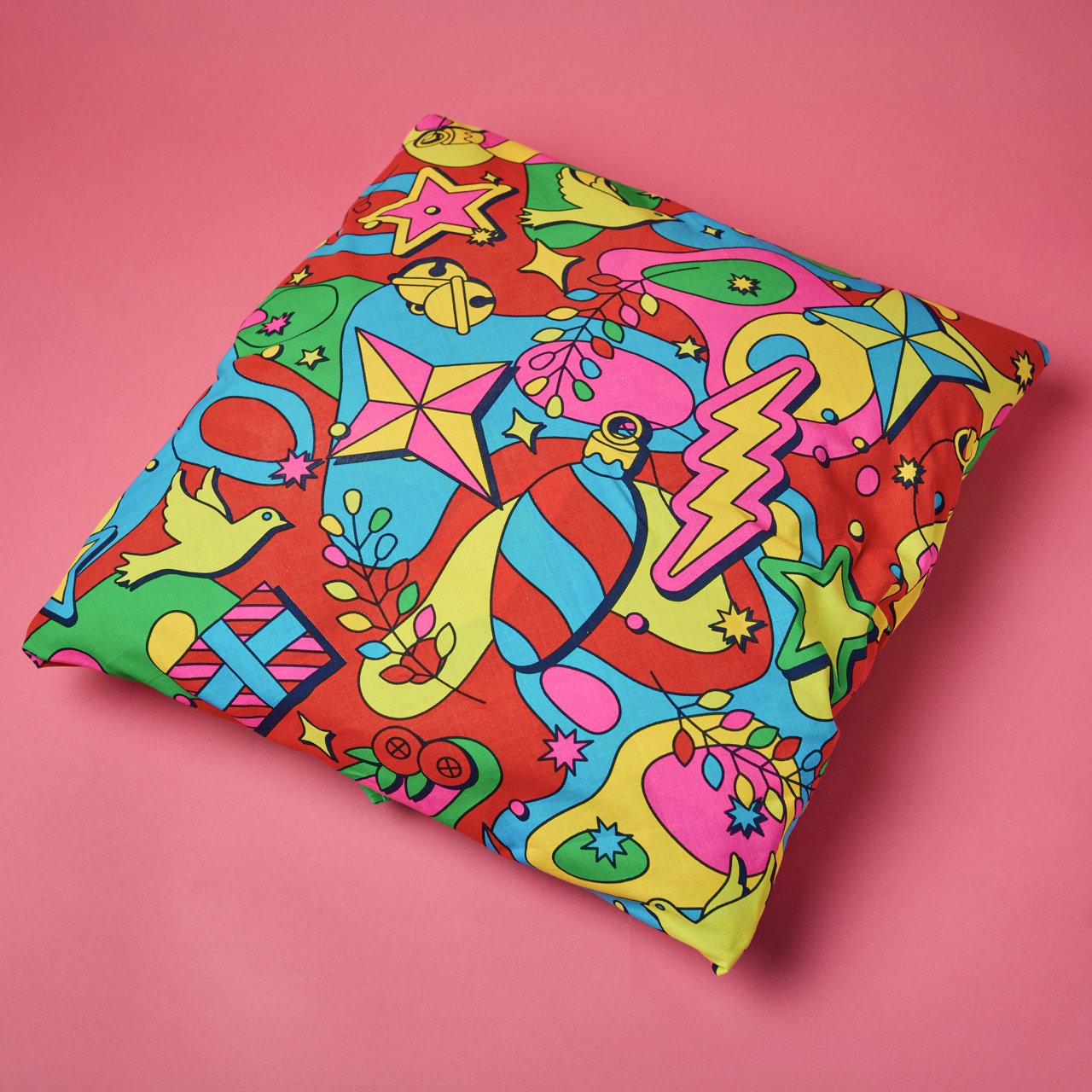 Multicoloured, pattered Lush Knot Wrap on a bright coral pink/red background.