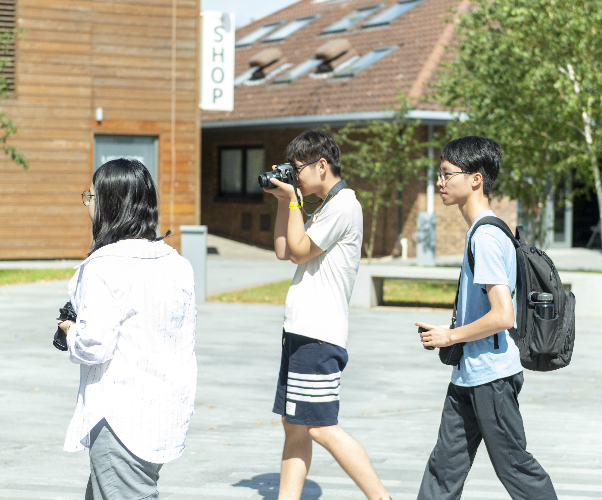 Three International students walking across the main courtyard on AUB campus with cameras.