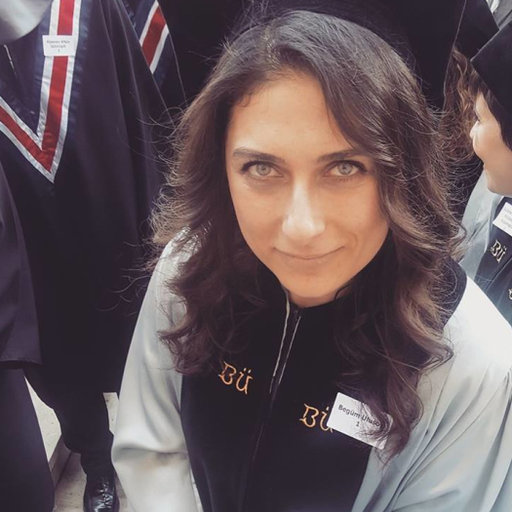 Woman with dark wavy hair wearing white jacket with black scarf, Union Jack flags visible in background
