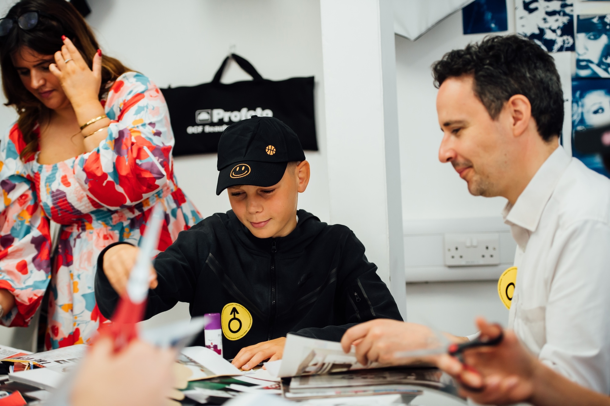 A young person sitting at an arts and crafts table with an adult either side of them.