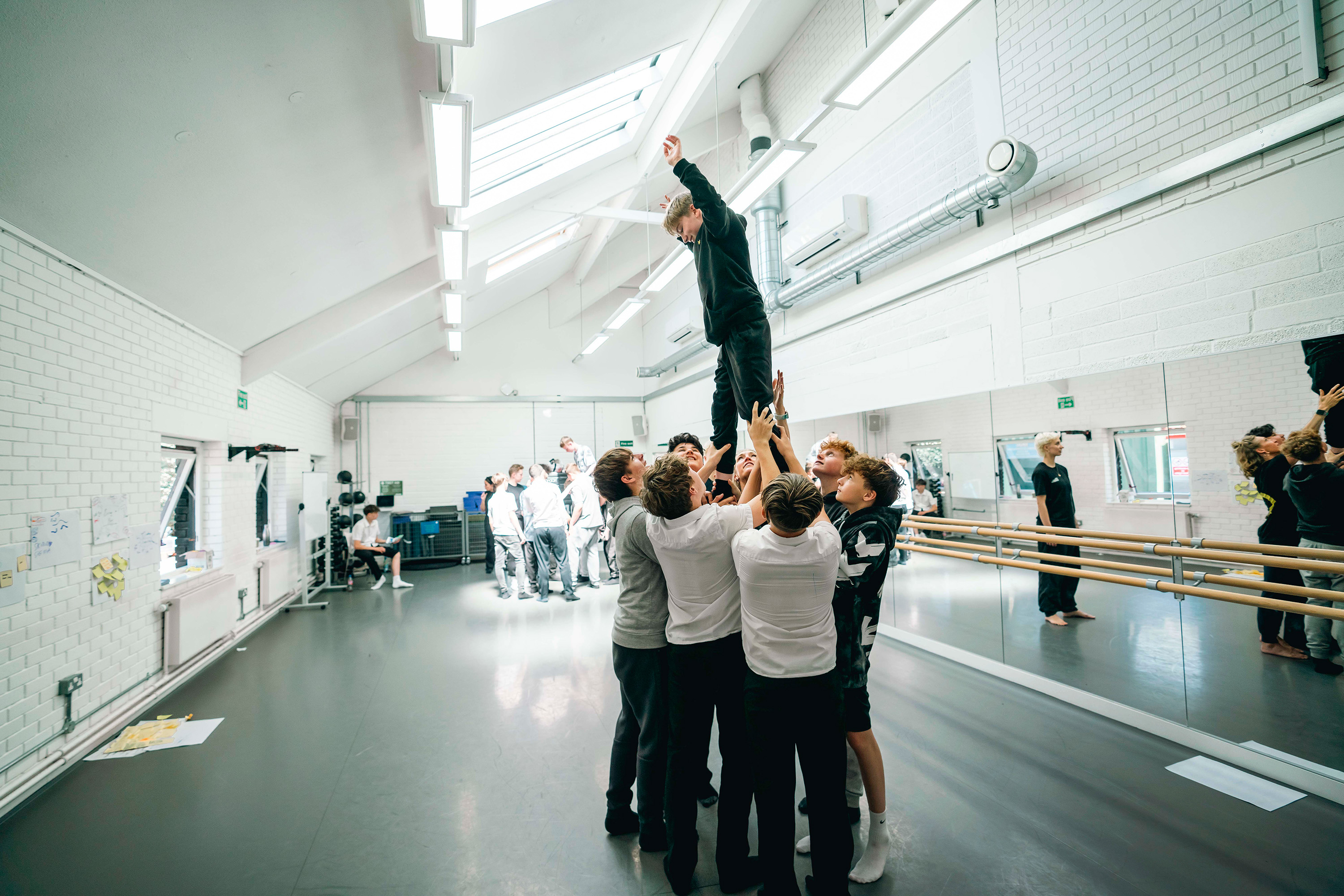 A group of boys in a dance studio at AUB. The boys are holding up one boy who is standing in the centre like a pyramid
