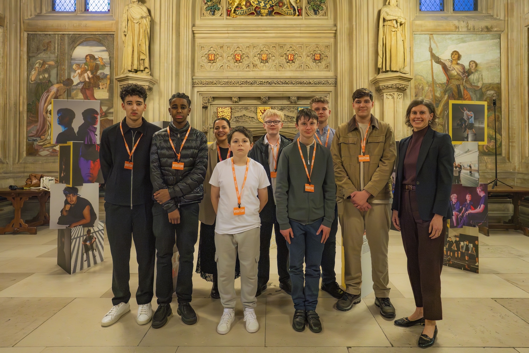 Group of nine people wearing orange lanyards standing in ornate church interior with painted religious scenes, golden columns, and decorative walls.