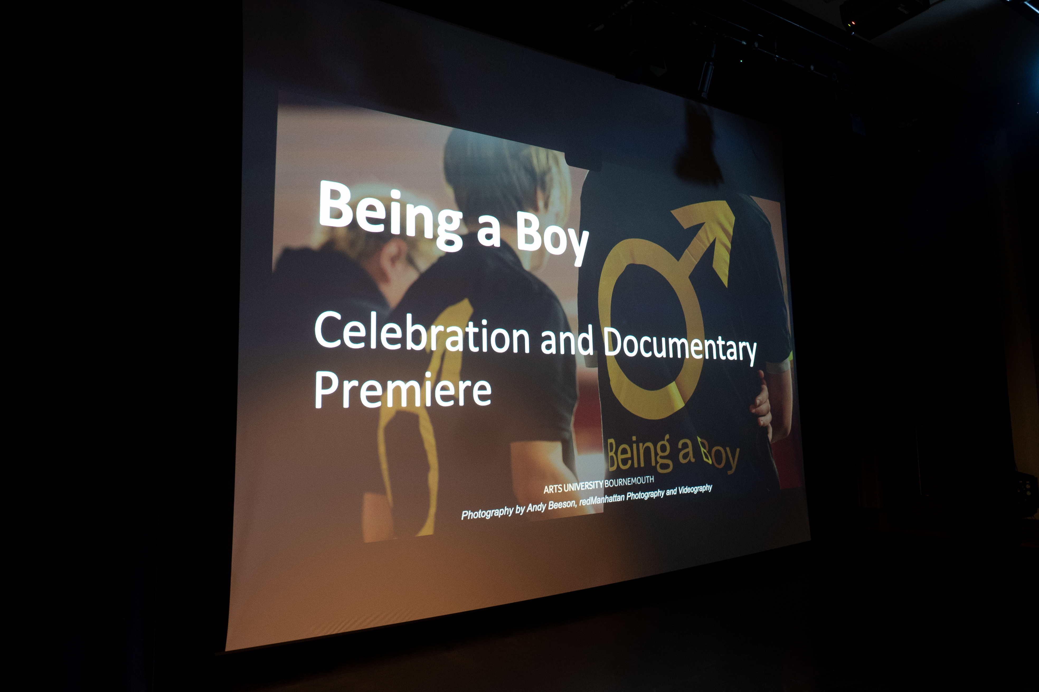 Welcome screen on stage which reads "Being a Boy - Celebration and Documentary Premiere"