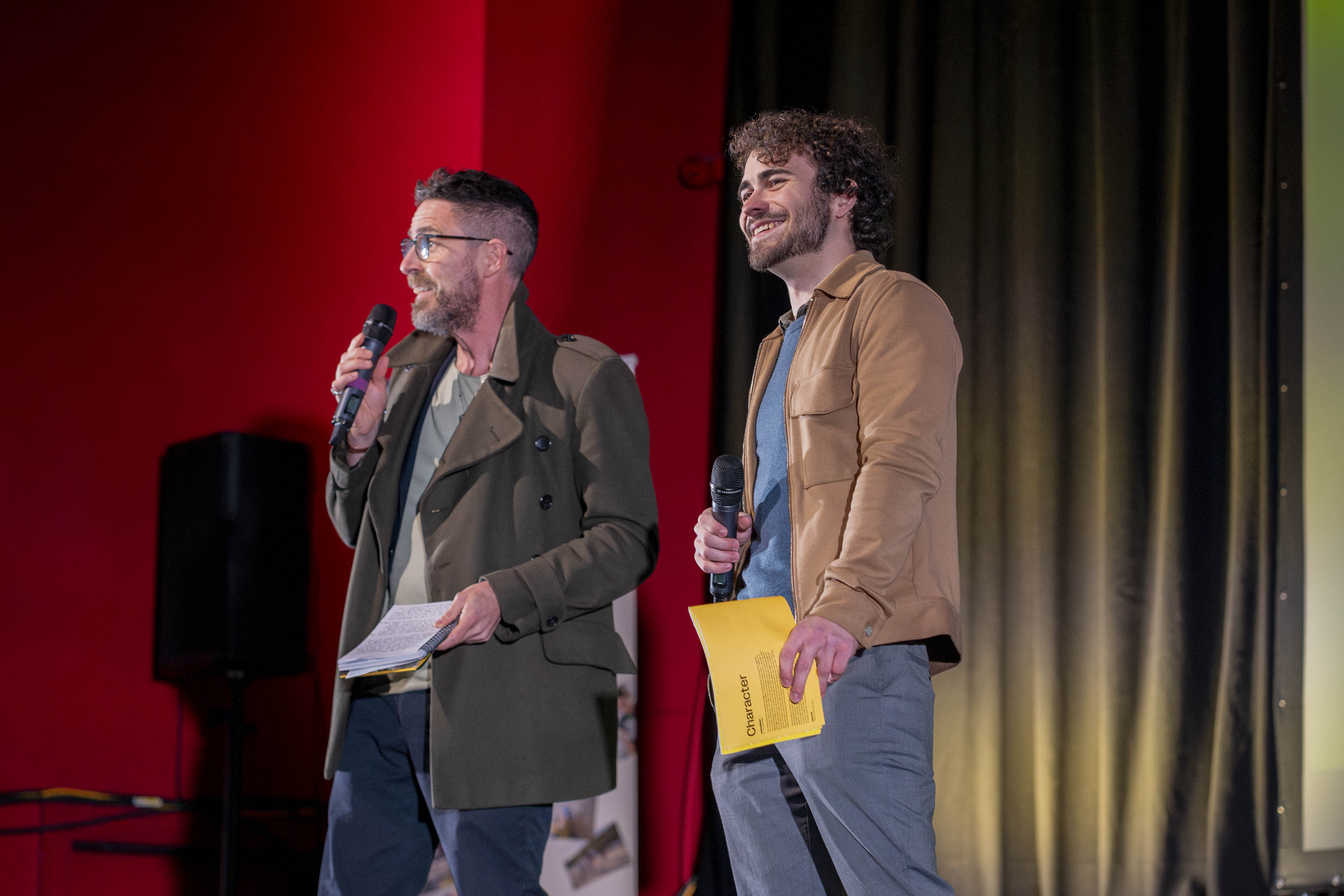 2 members of staff on stage speaking into microphones