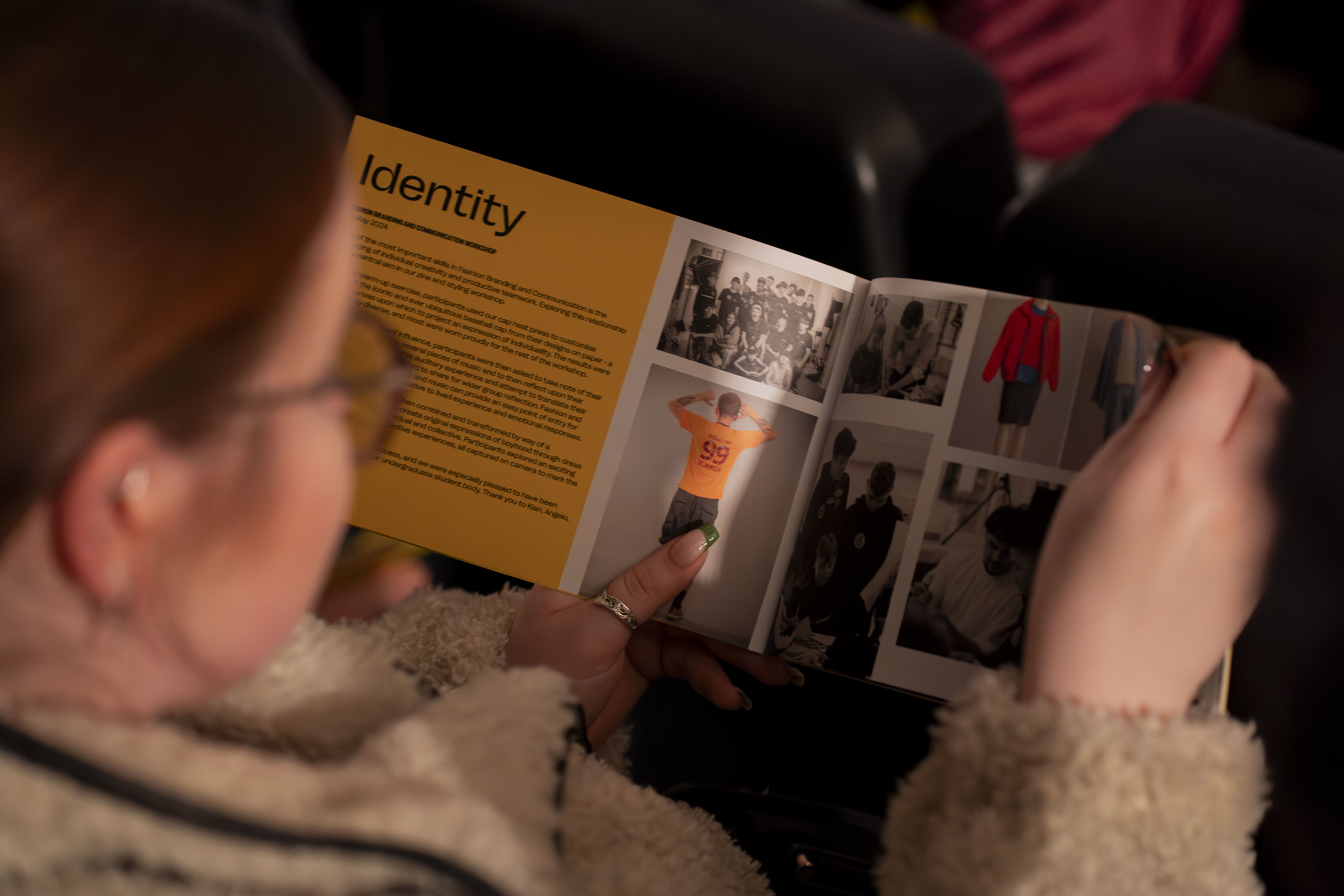 Close-up of a person reading a Being a Boy workshop flyer. The flyer is open to a section entitled "Identity".