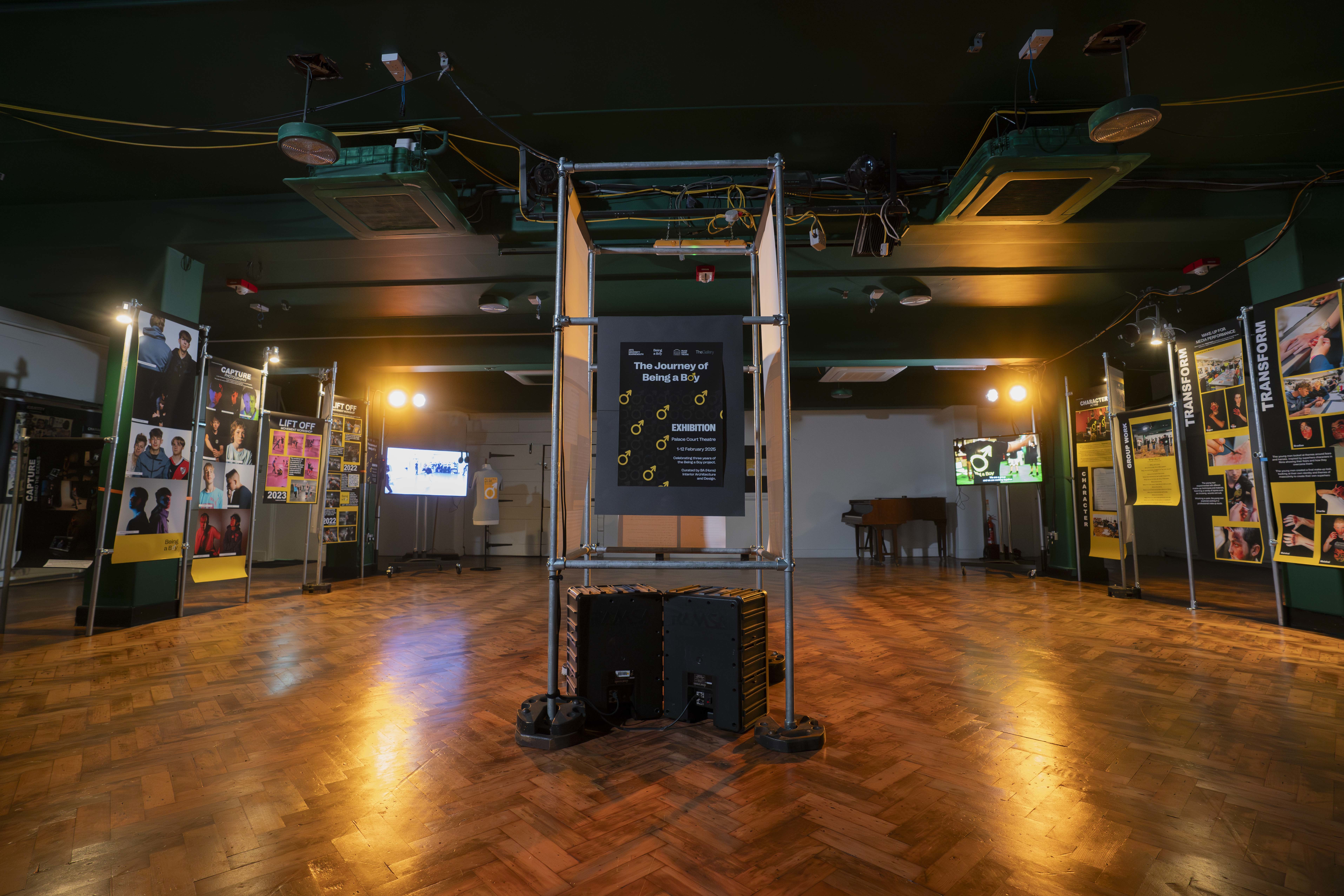 A series of exhibition stands with different exhibits and posters around the sides and in the centre of a parquet floor at the Palace Court Theatre, Bournemouth.