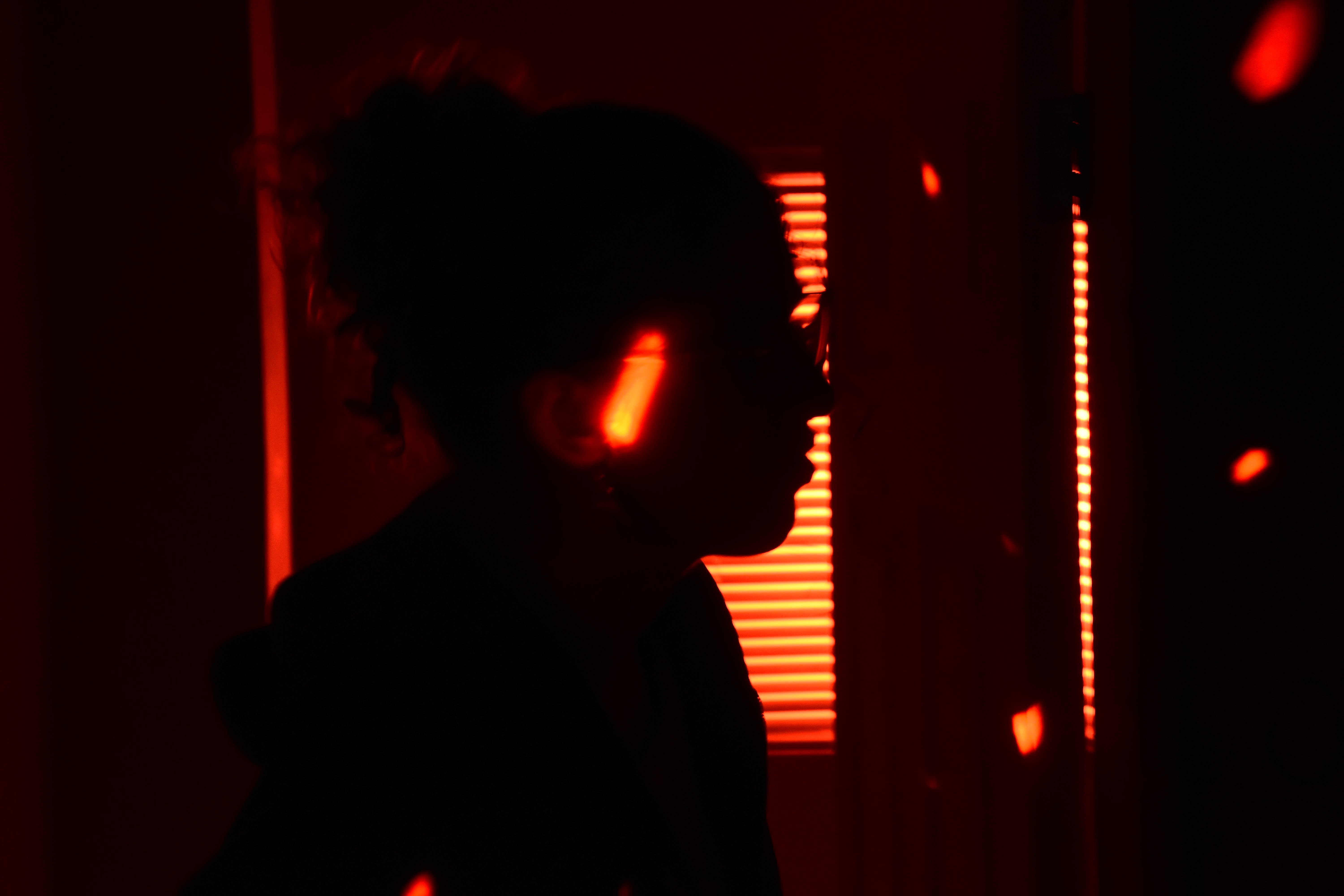 Close-up of a silhouette of a BA (Hons) Film Production student with orange light feeding through in the background.