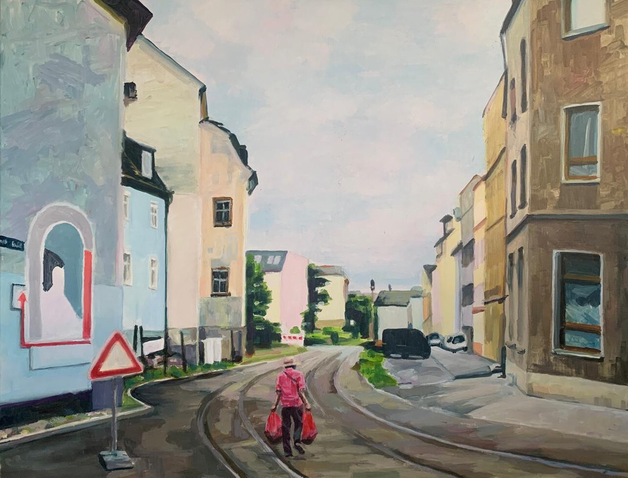 Watercolour painting of street scene with pale pink and blue buildings, figure in red walking on grey road, soft pastel sky background.