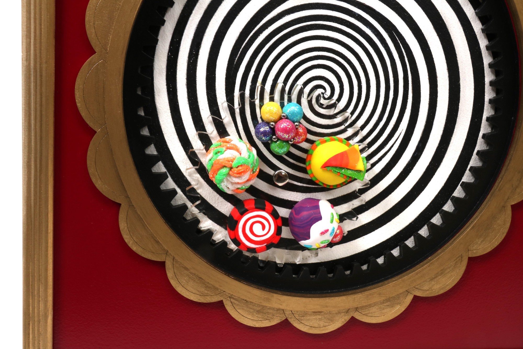 Close-up of an optical illusion-style spiral, with five assorted sweets attached to it.
