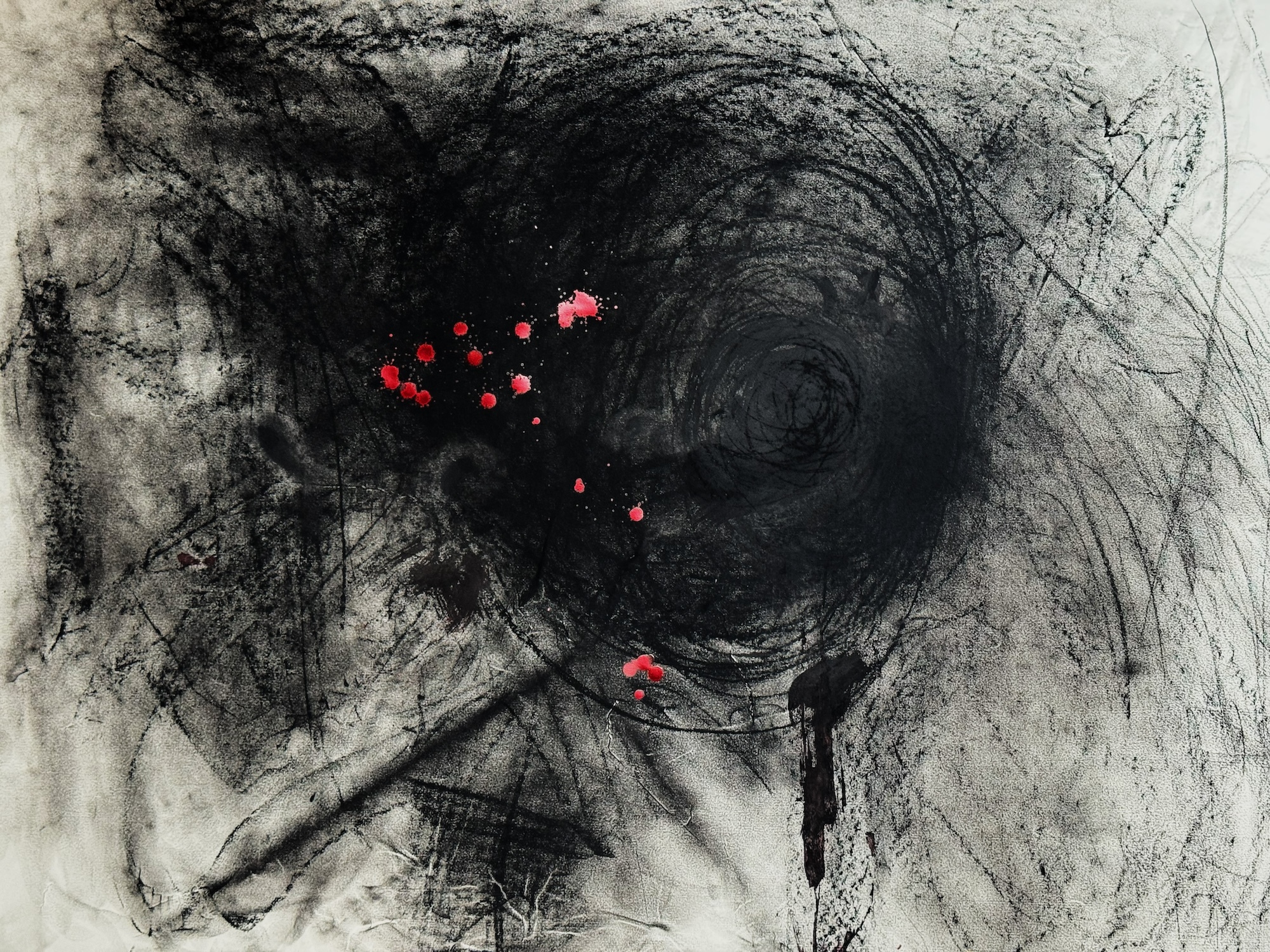 Abstract artwork made up of a mass of black, with spots of red near the centre.
