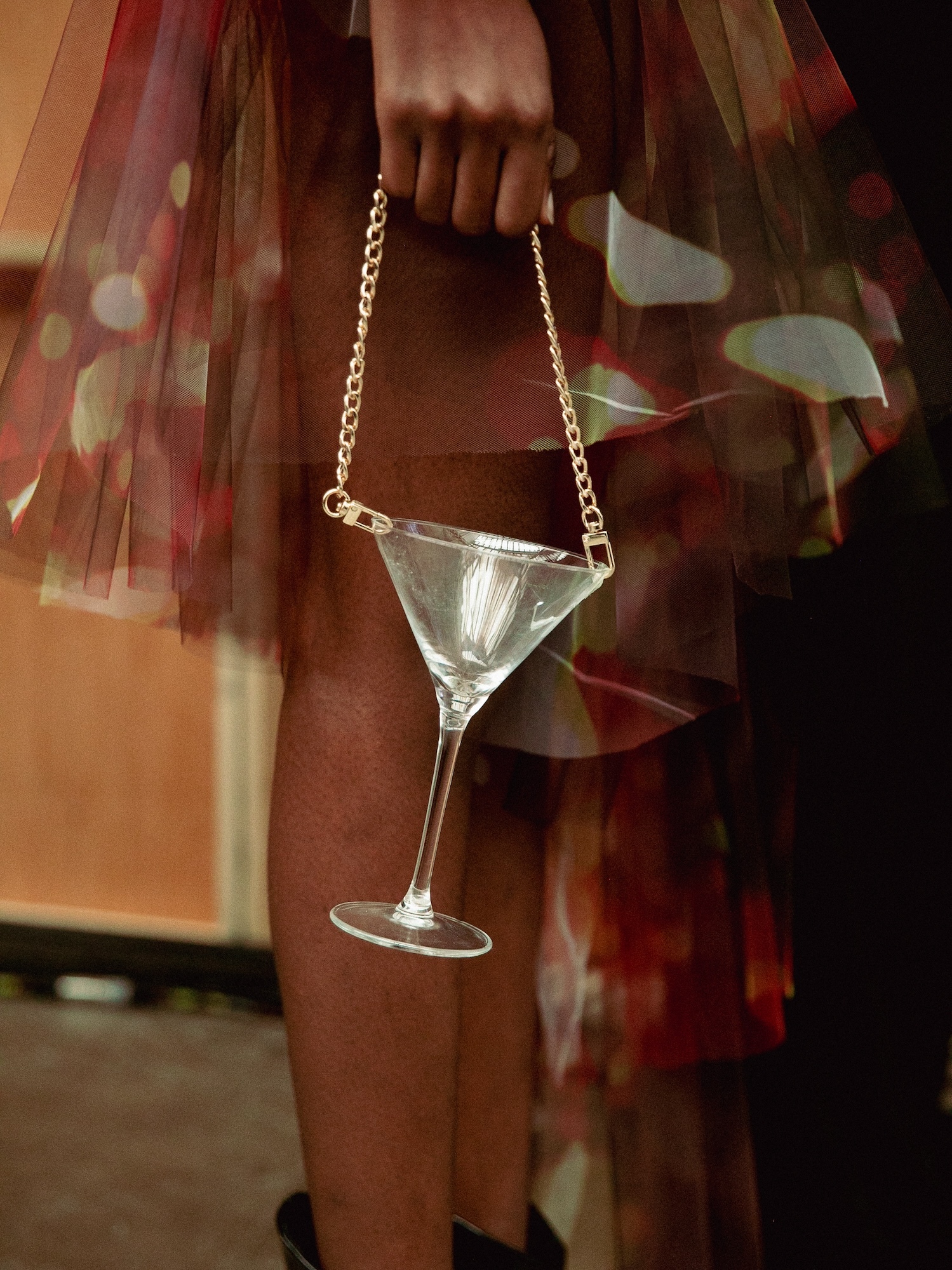 Close-up of a model holding a martini glass from a chain like a handbag or purse.