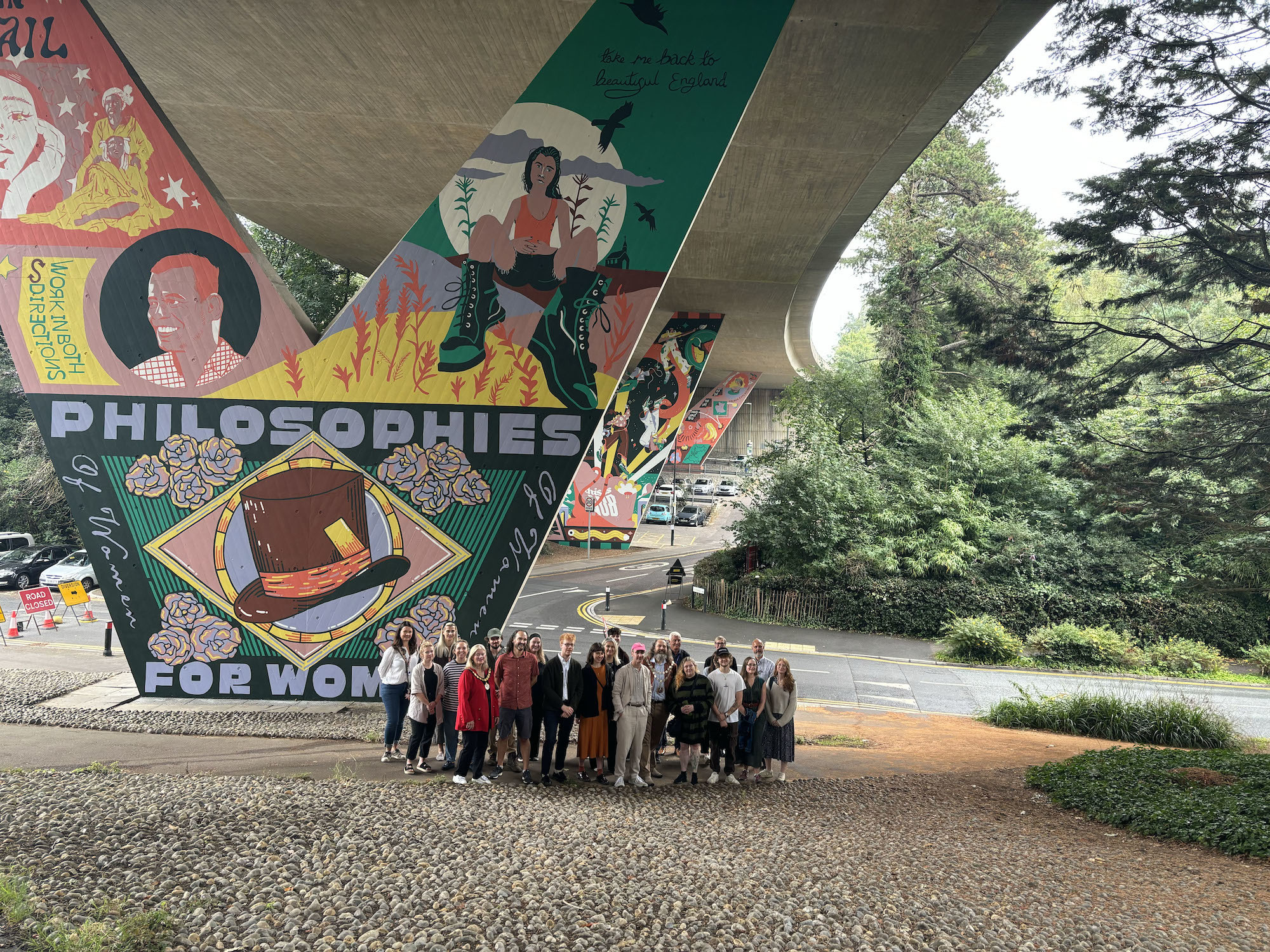 A large group of AUB staff, students and BCP council officials gathered for a photo outside a large mural under Braidley Road flyover in Bournemouth.