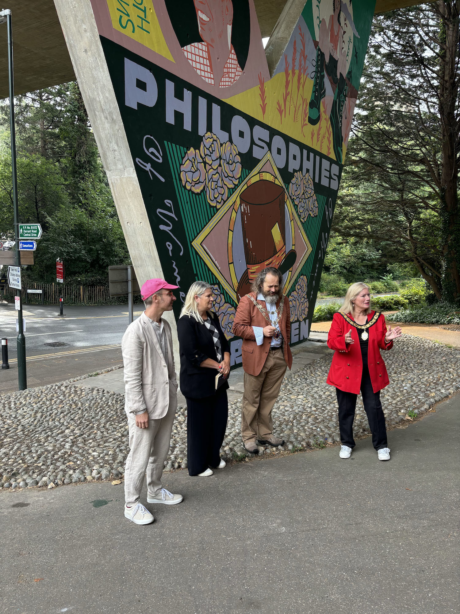 V Larkin, L Mann, Cllr G Farquhar and Cllr L Dedman stand and giving speeches by a large mural on a pillar of a flyover in Bournemouth.