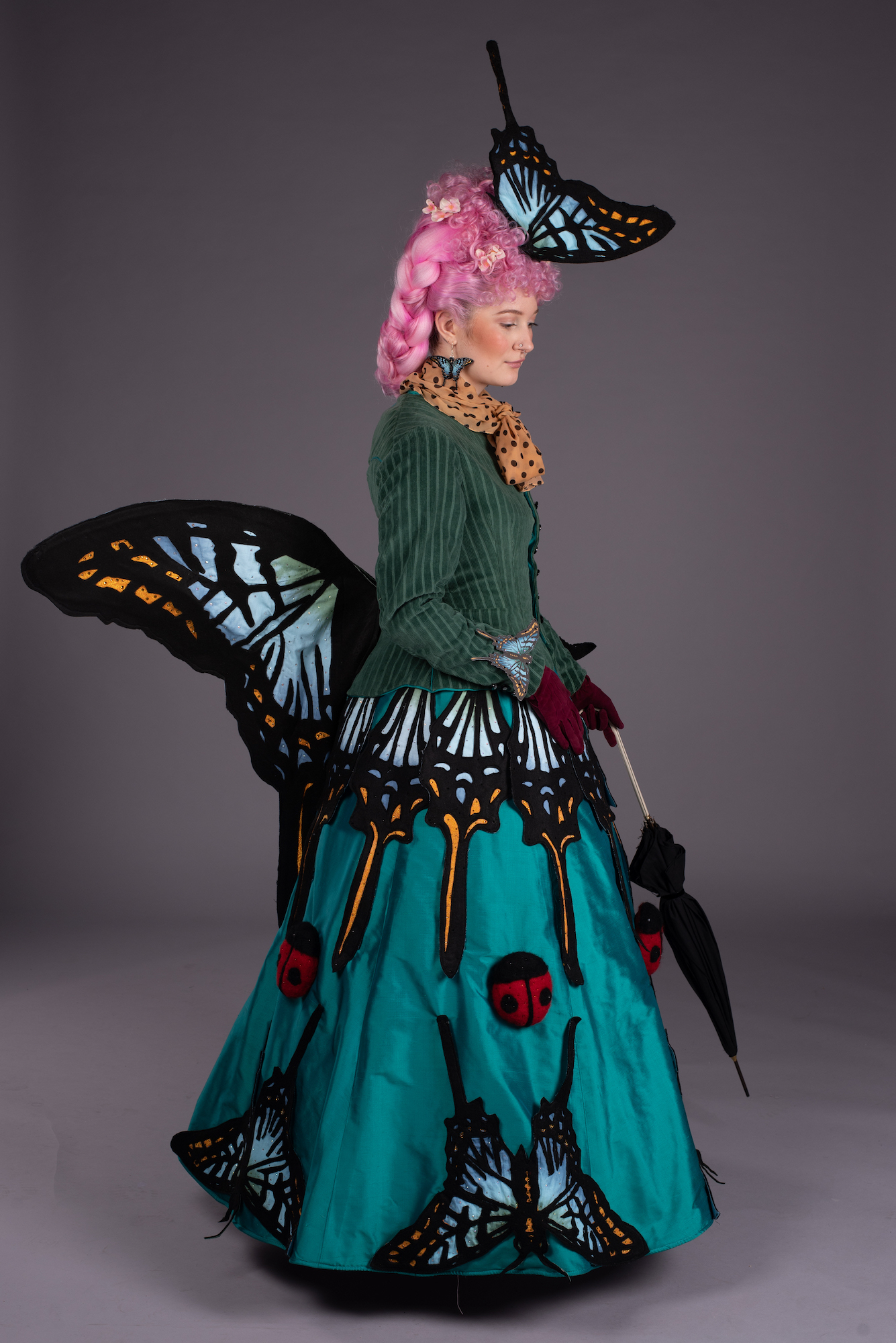 Model photographed from the side wearing a 19th century style gown and headdress inspired by butterflies.