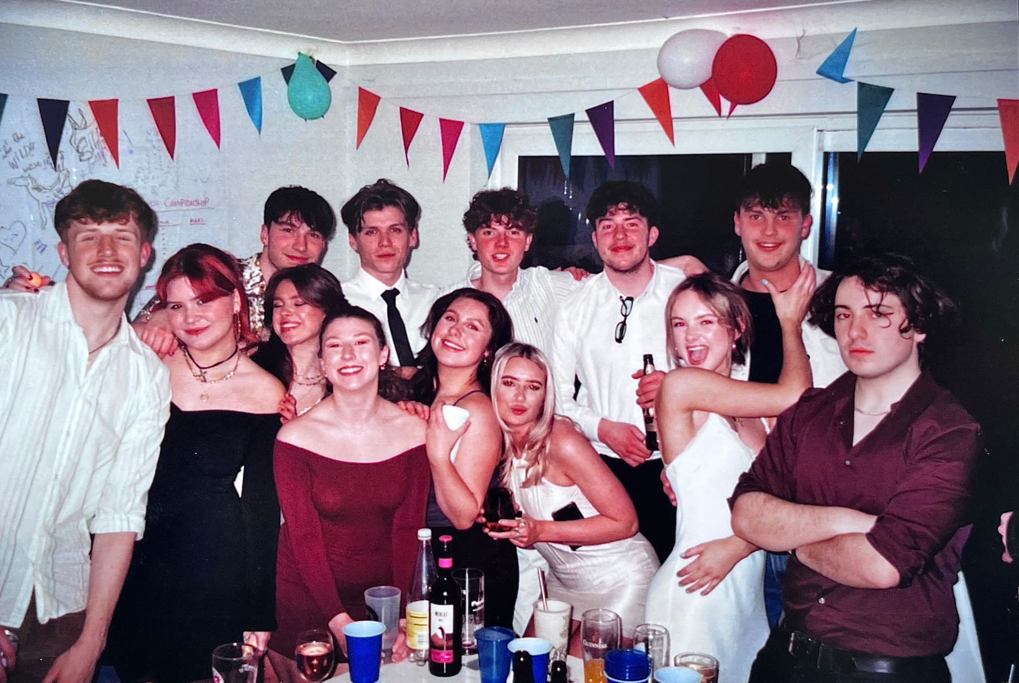 A group of AUB students posing for a photo at a party with balloons and bunting in the background.