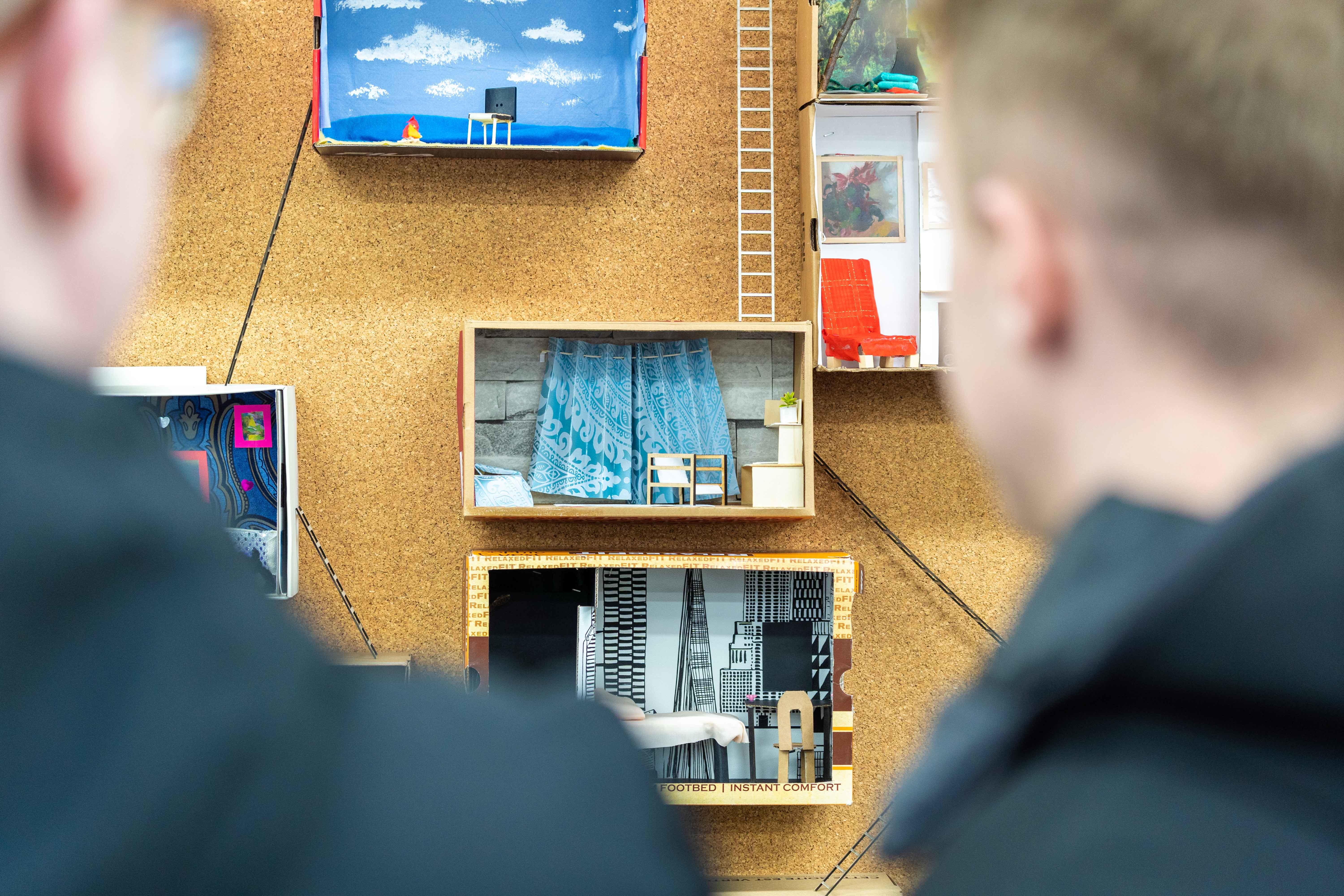 Students examine a wall-mounted dolls house diorama