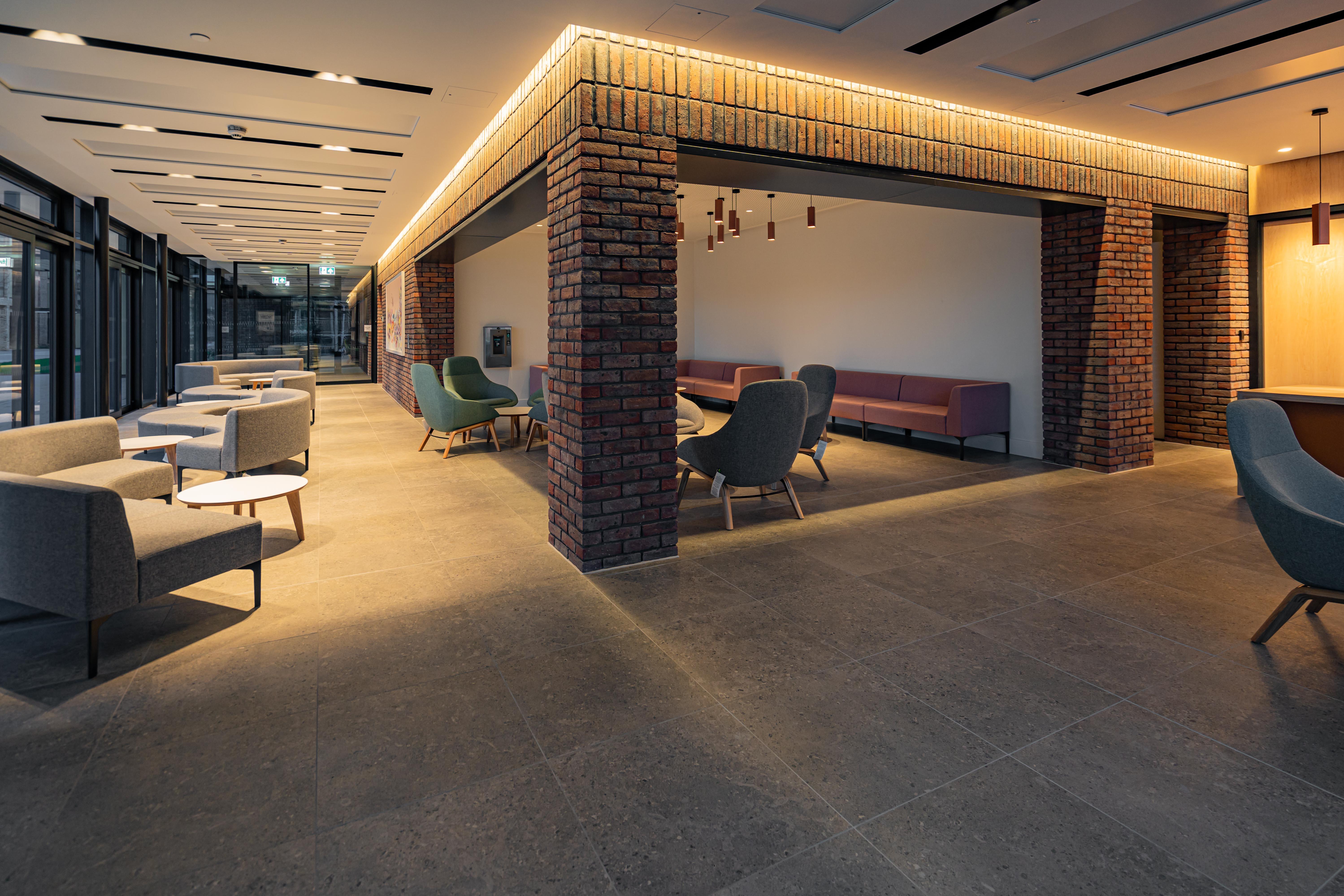 A long L-shaped room with a seating area with exposed brick pillars.