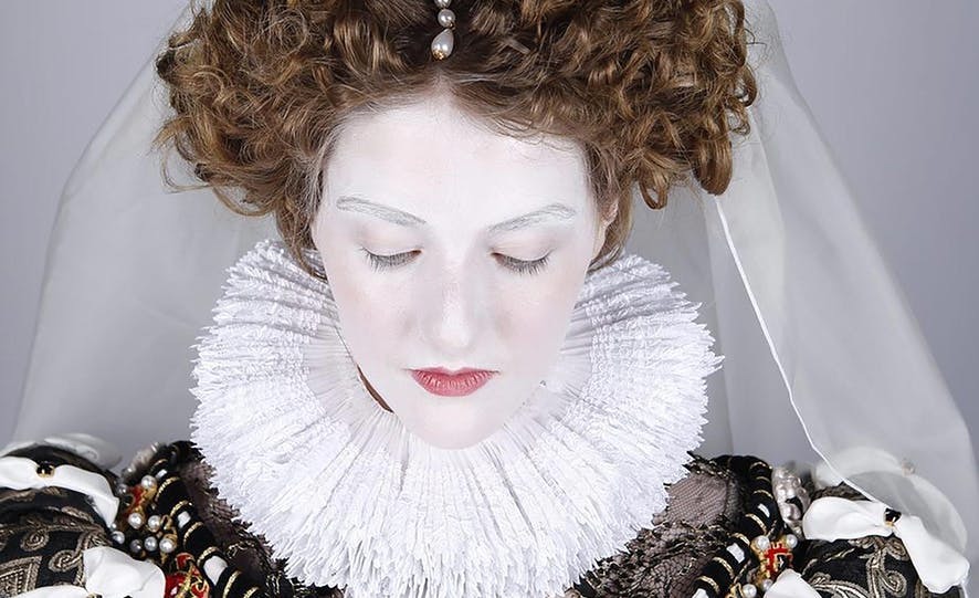 Close up image of a model in period dress with an ruffle collar