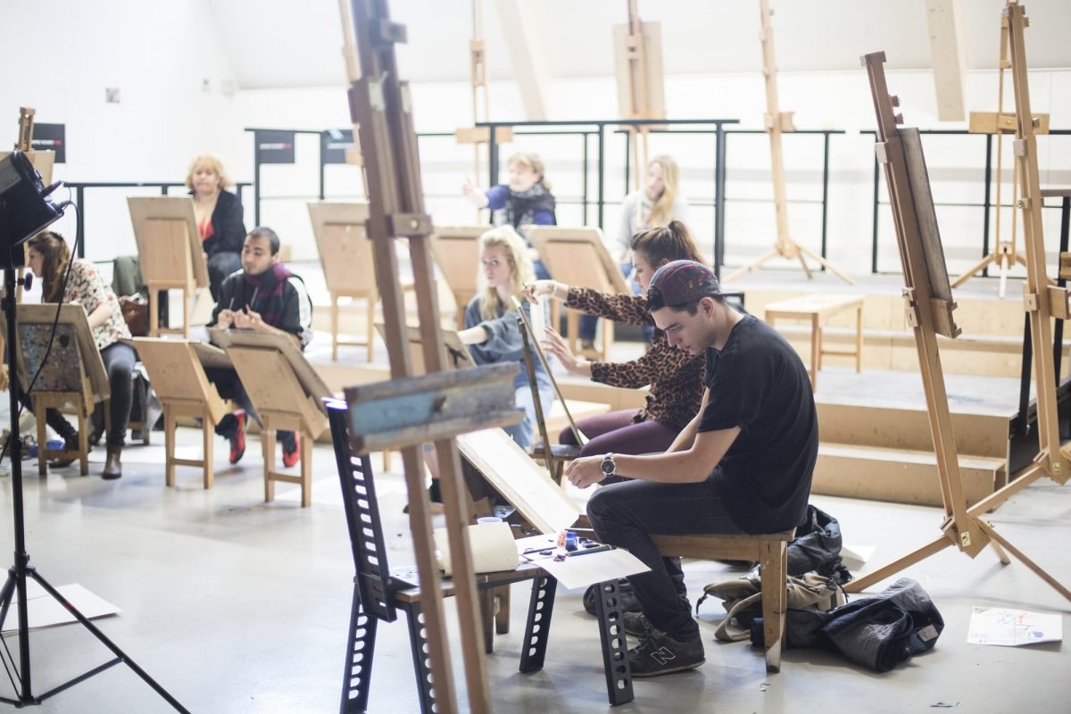A group of students sitting at easels in AUB's Drawing Studio and painting.