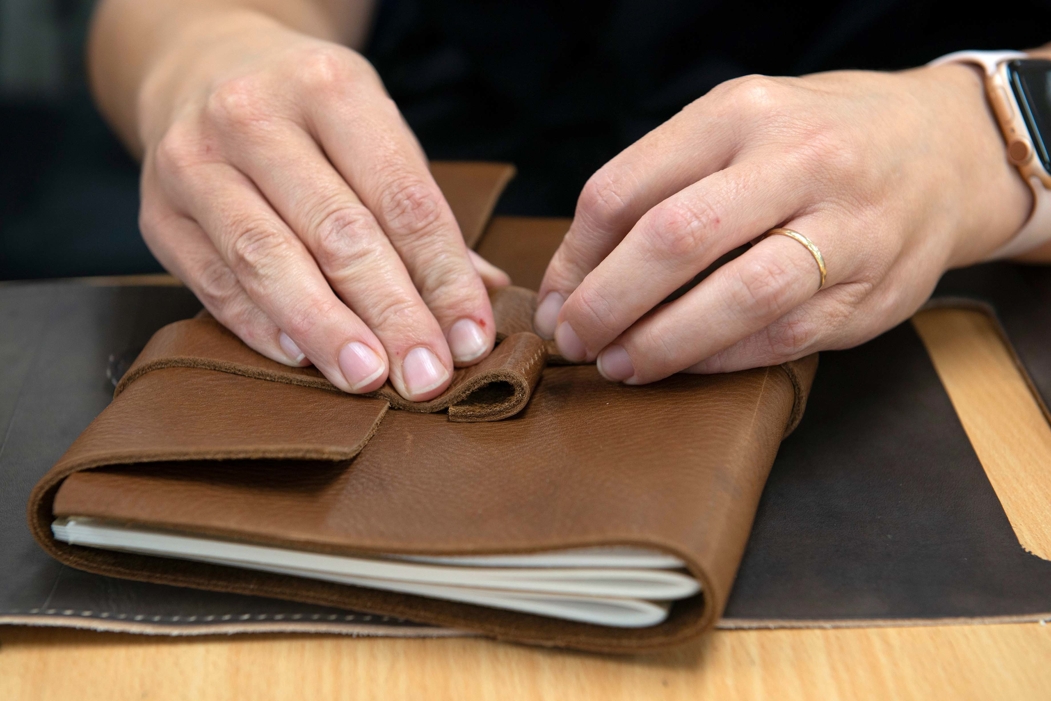 Hands over a leather bound notebook