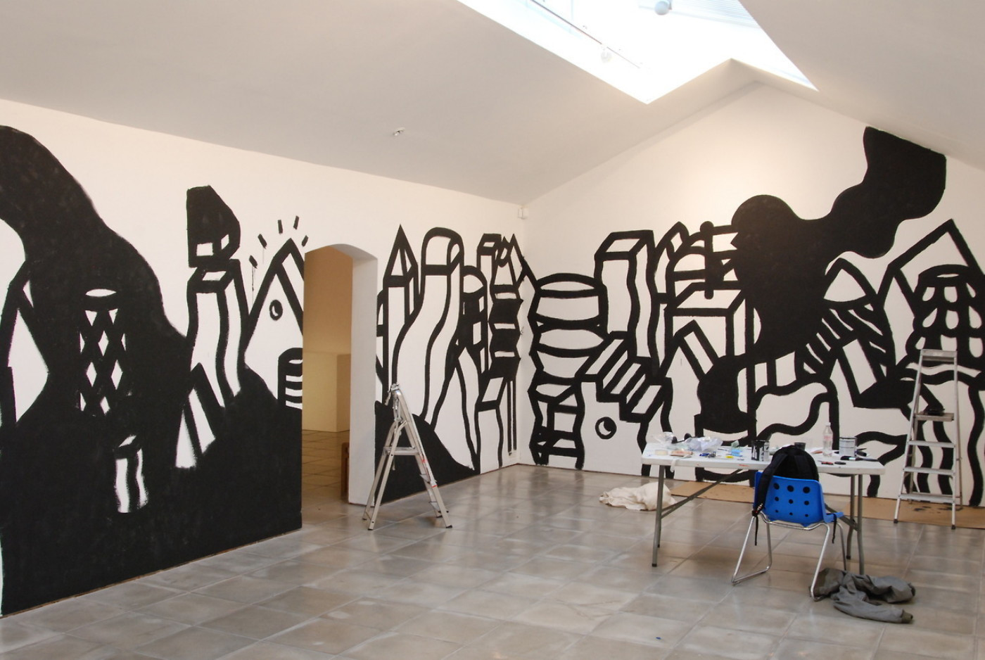 A studio space with bold black and white illustrations painted on the wall.