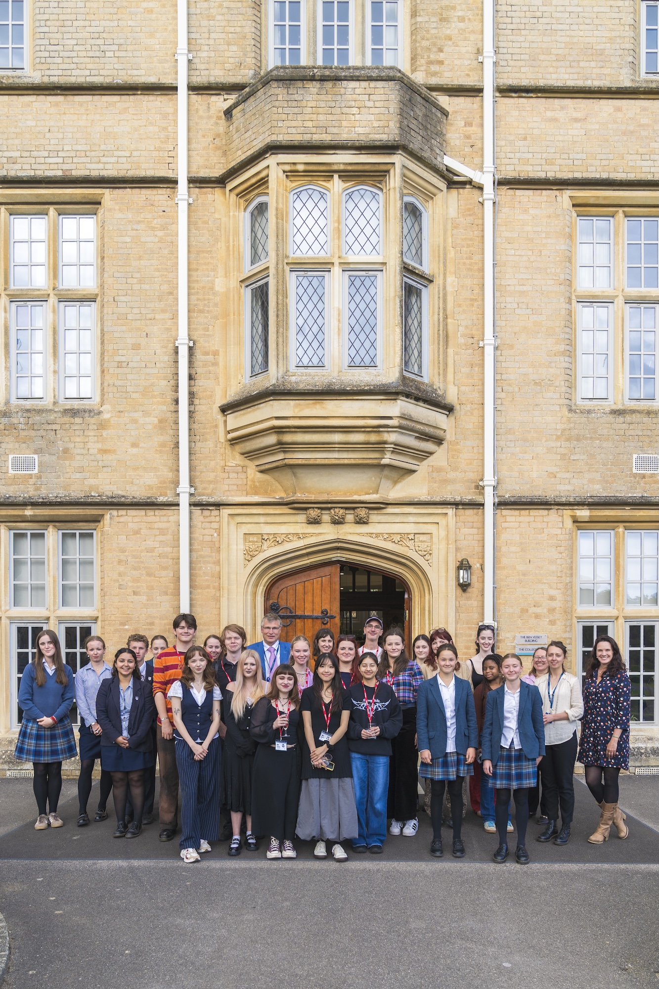 A large group of staff and students from both Arts University Bournemouth and Canford School pose for a photo outside the school building.