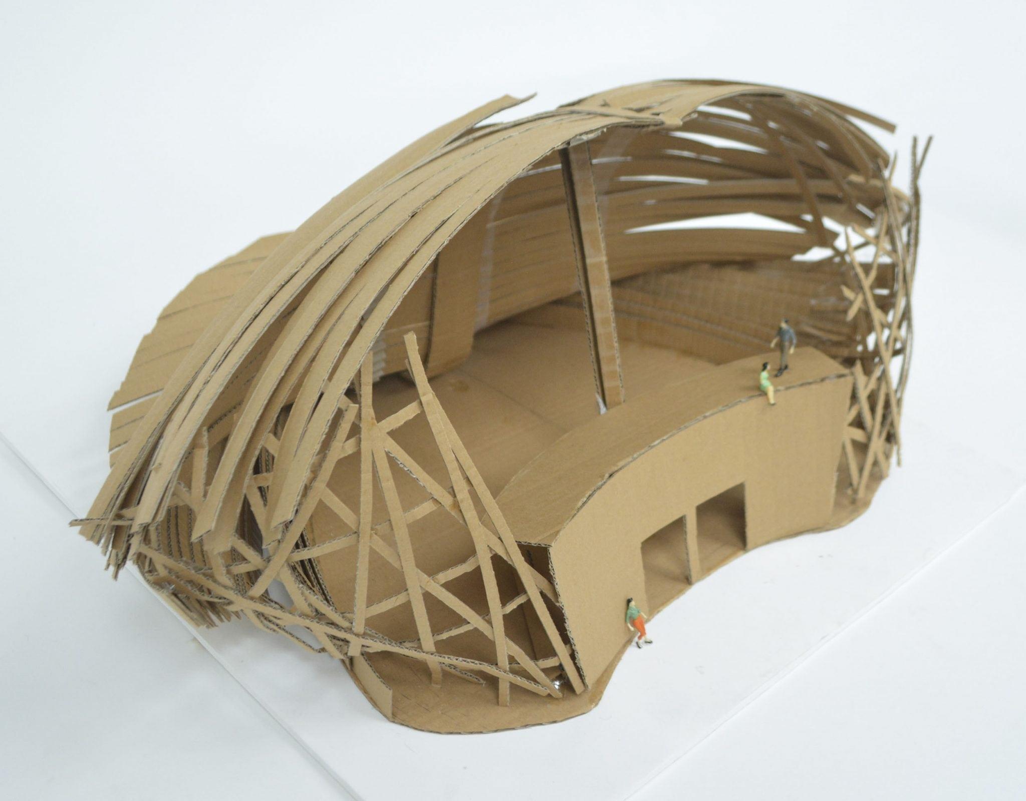 A cardboard model of a large building with a rounded roof and two doors at the bottom