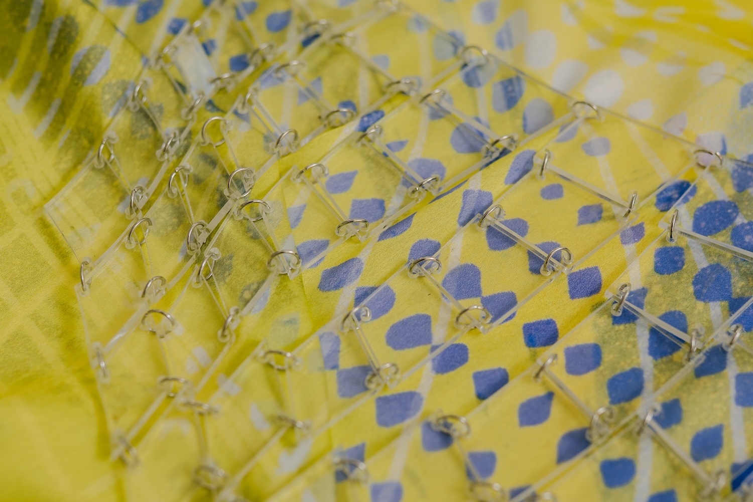 Yellow fabric with blue polka dots and gathered sections creating textural folds and creases across the surface.