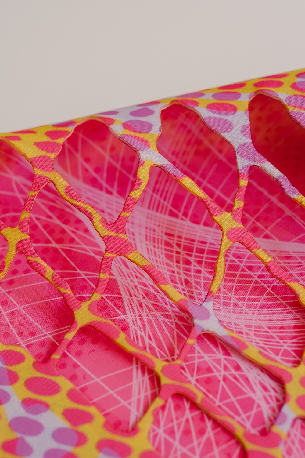 Crumpled fabric with bright pink heart pattern on yellow background, featuring white grid lines overlaying the hearts.
