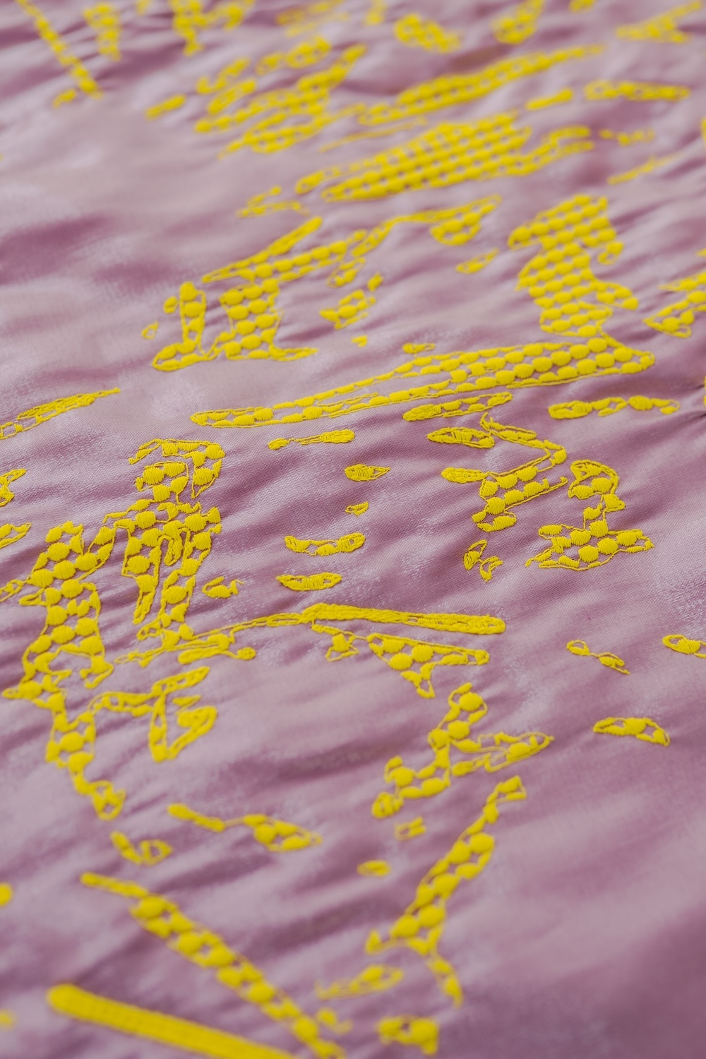 Bright yellow dotted patterns scattered across soft pink and purple striped fabric surface, creating geometric contrast.