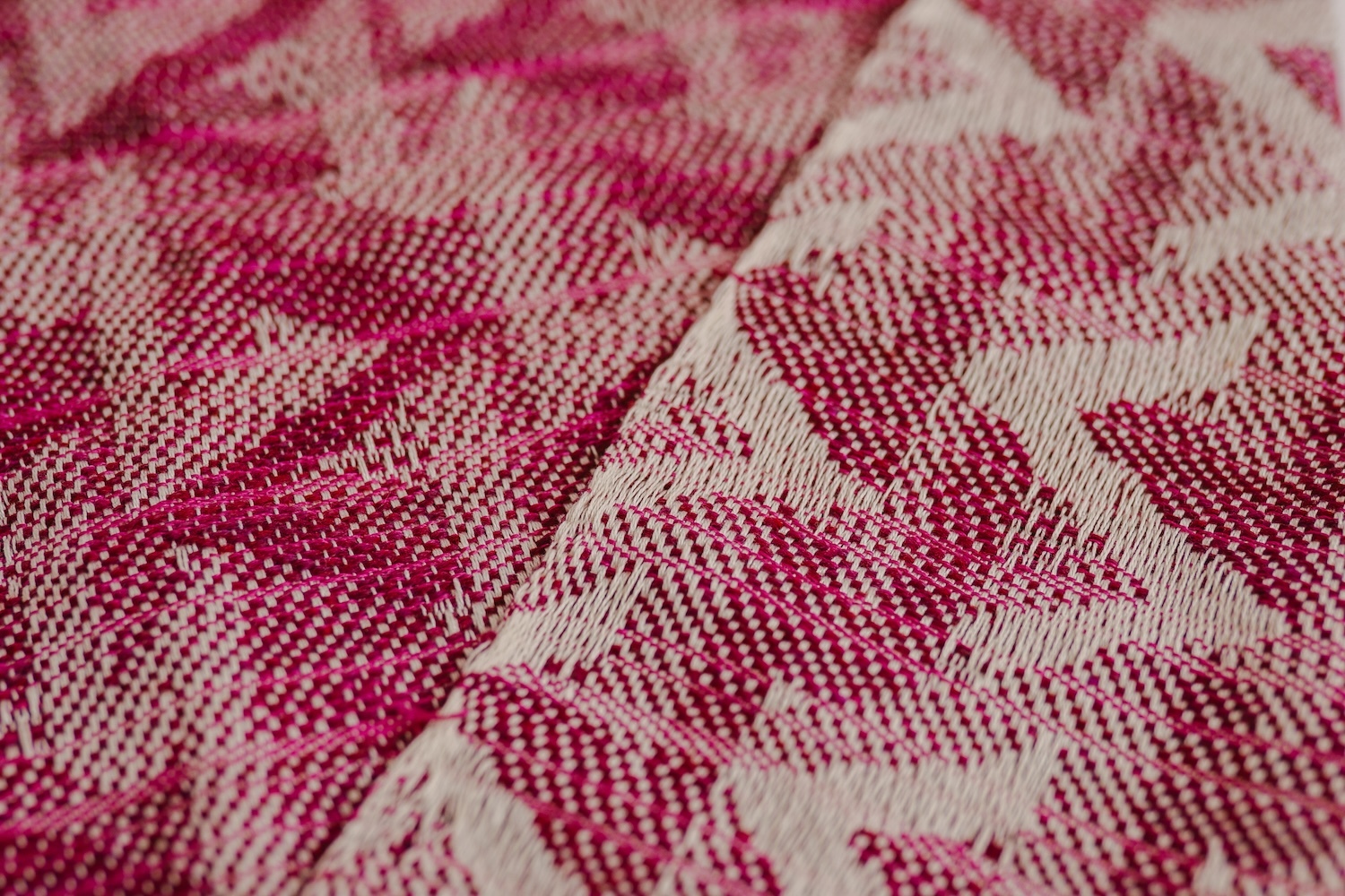 Close-up of red and white patterned fabric with geometric zigzag design and textured weave creating diagonal lines and angular shapes.