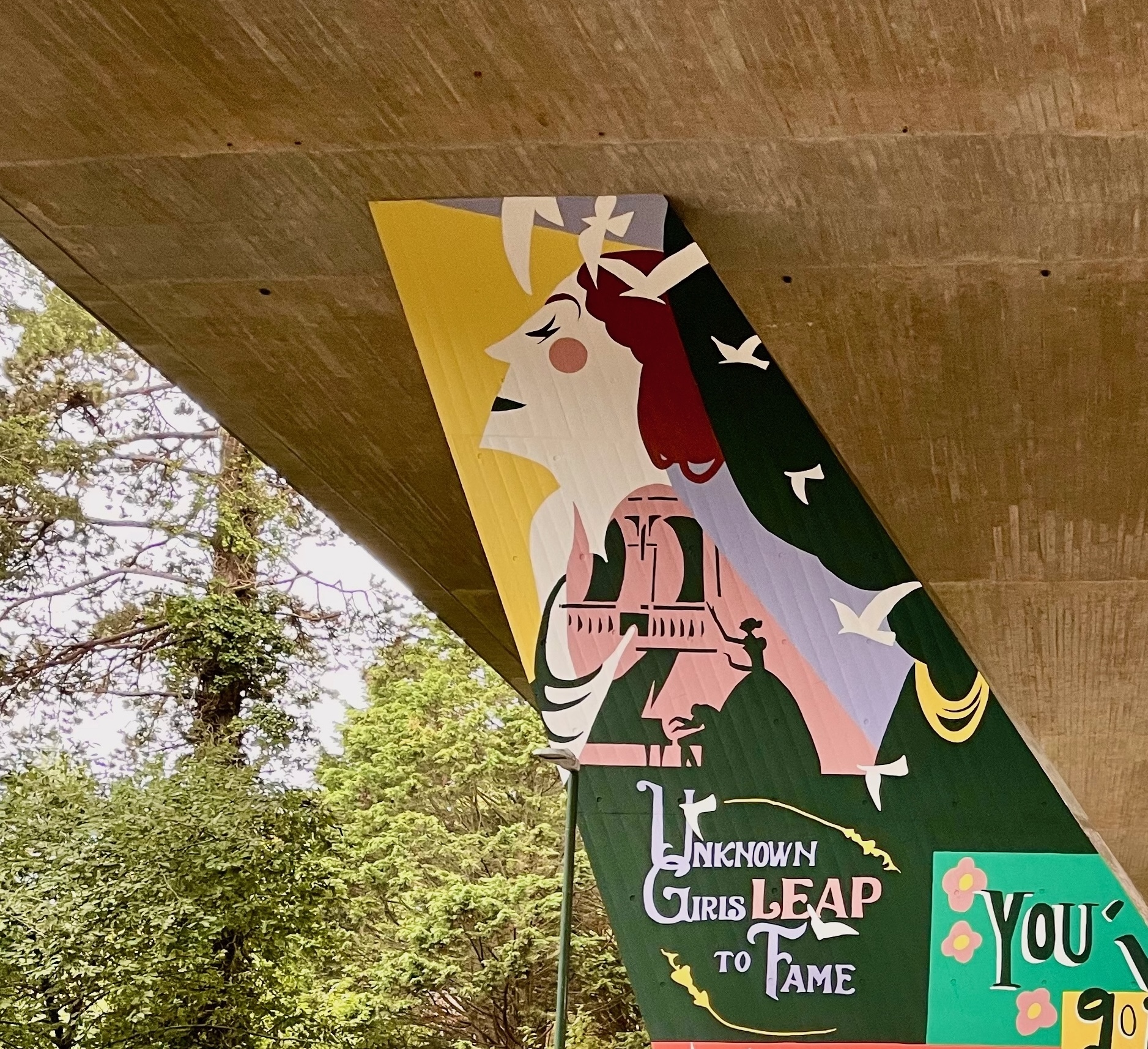 Part of a mural on a flyover pillar wall. Side profile of a woman's face, with a silhouette of a singer and piano player under it. Text reading "Unknown girls leap to fame" appears at the bottom.