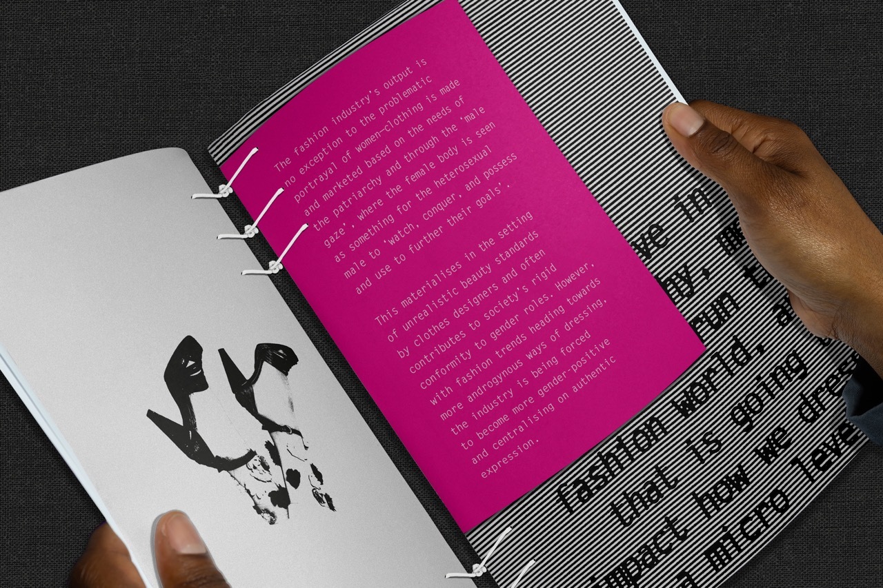 Person holding the magazine open on a double page with a filtered image of shoes and an overlay of text discussing society’s move towards more androgynous ways of dressing.