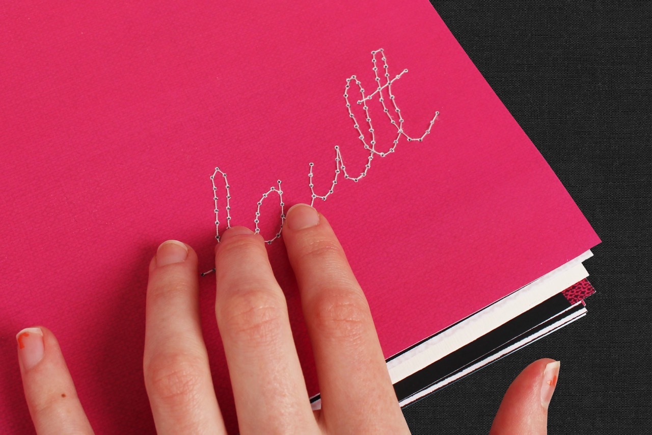 Photograph of a hand interacting with the hand-sewn ‘Fault’ type on the magazine’s front page.
