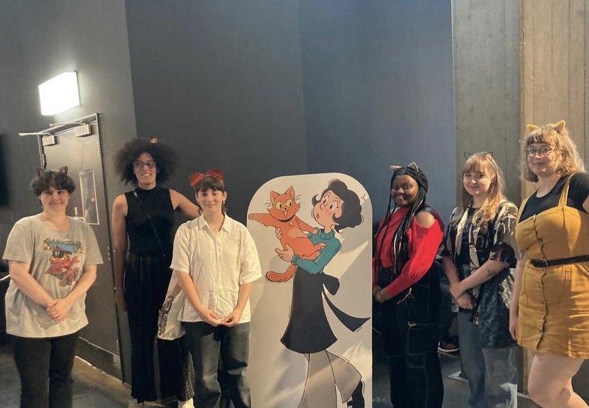 Six AUB students standing either side of a standee of an animated girl holding a cat.