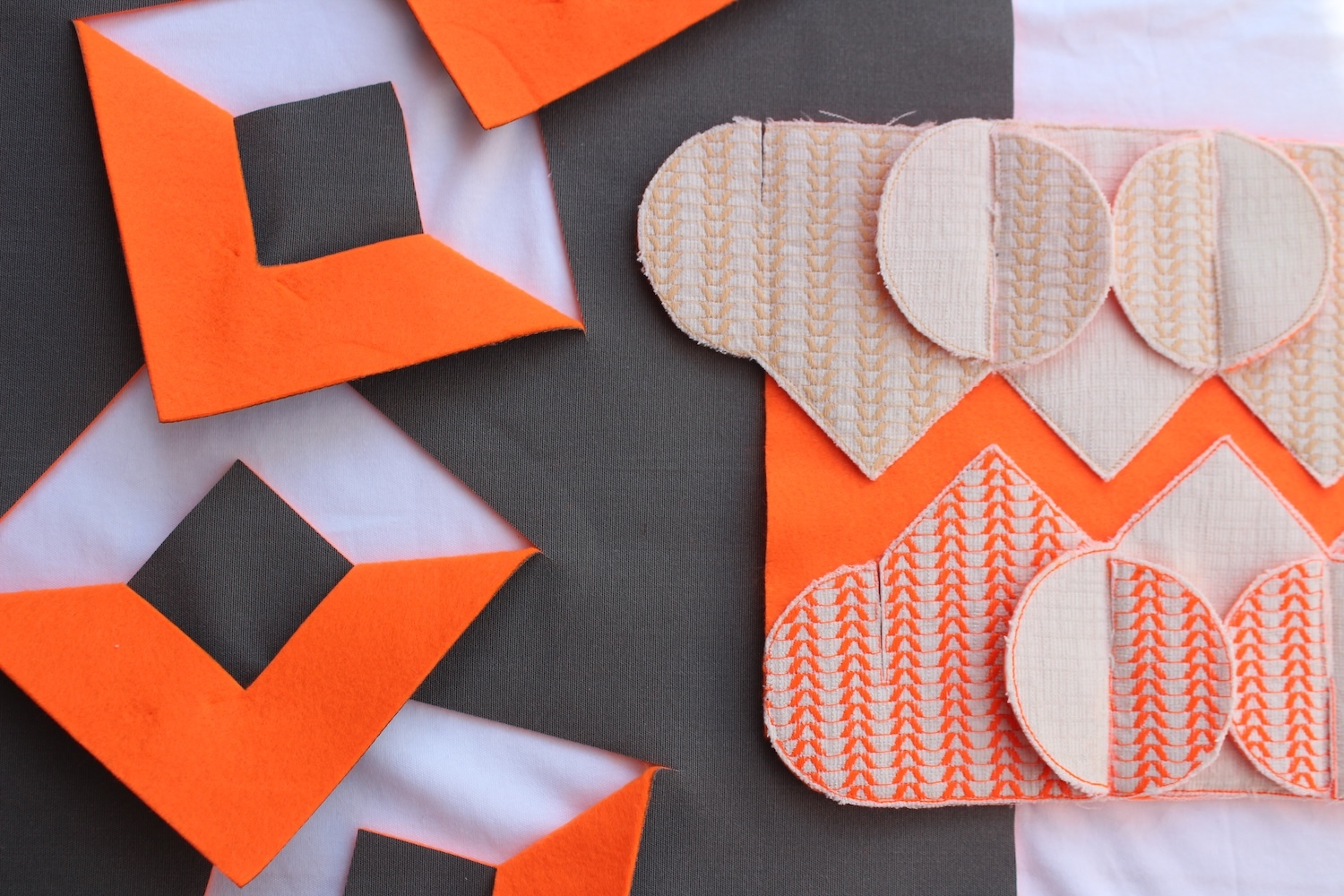 Orange geometric shapes with black squares alongside beige heart-shaped cutouts with patterned designs on white striped background.