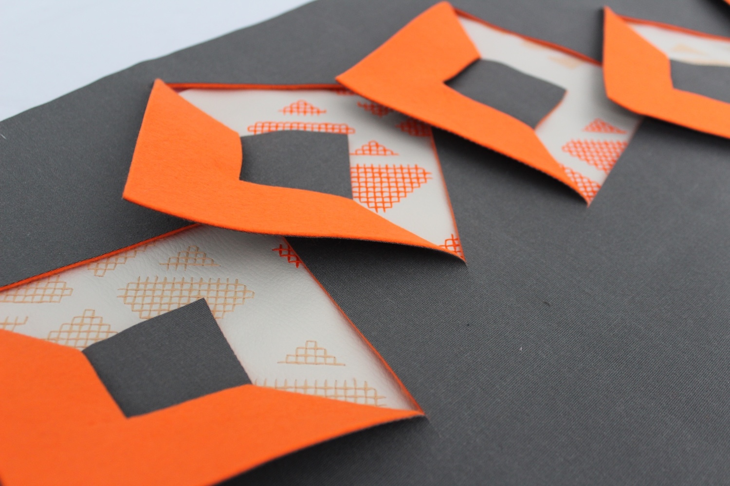 Orange paper houses with triangular roofs and square windows on dark grey surface, featuring red checkered pattern details.