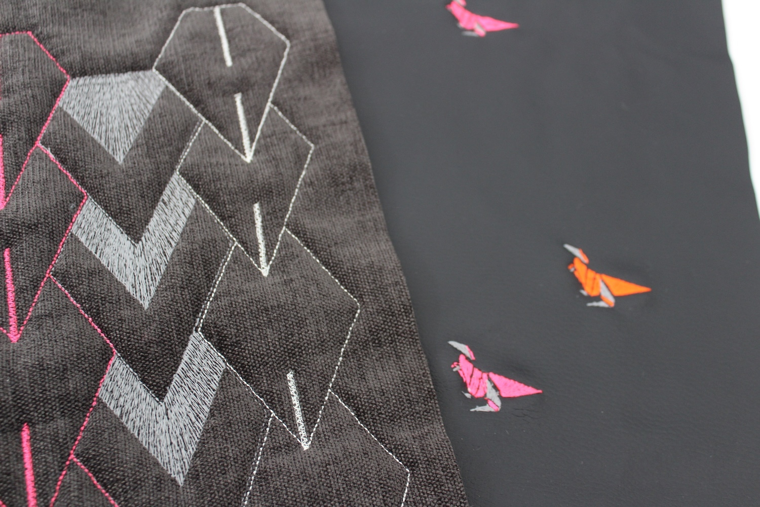 Grey geometric shapes with white outlines and zigzag patterns on left, three small coloured paper planes (pink and orange) on dark surface.
