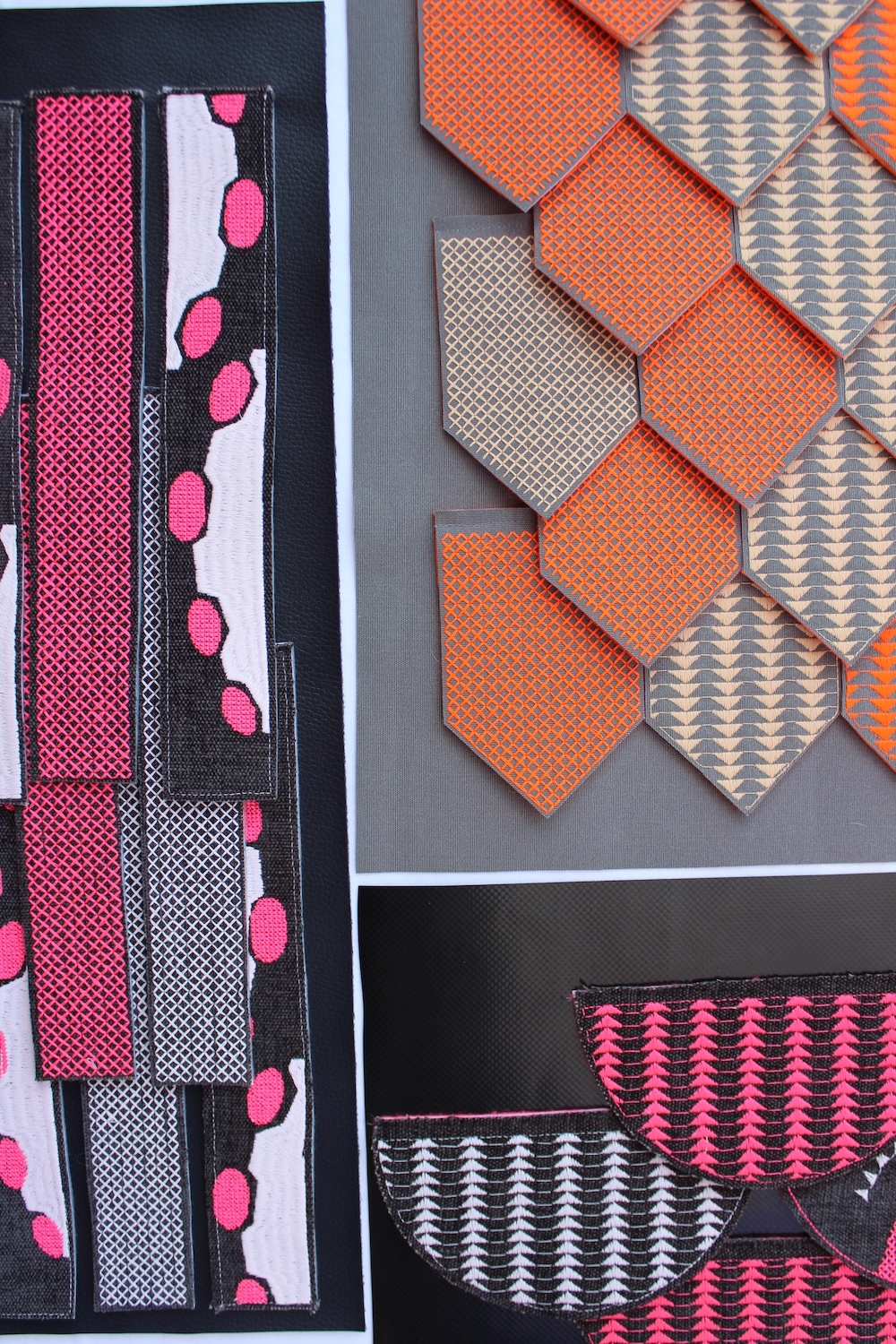 Collection of neckties displayed in boxes featuring pink polka dots, orange geometric patterns, and pink-white triangle prints on grey background.