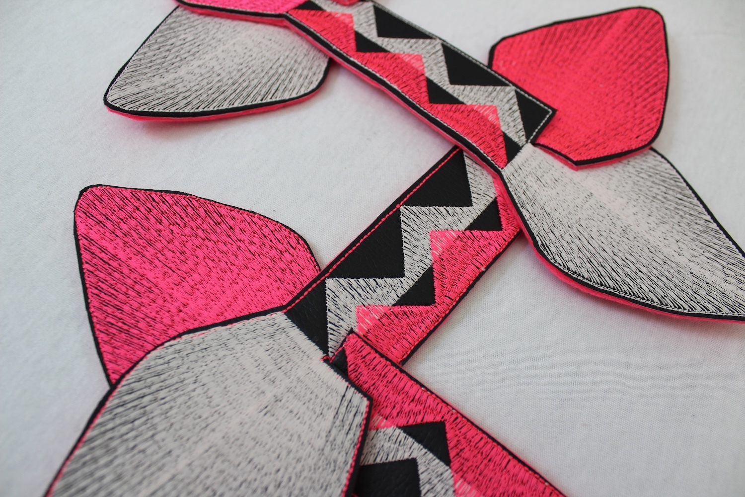 Red, grey, and black geometric fabric patches with zigzag patterns and triangular shapes arranged on white surface.