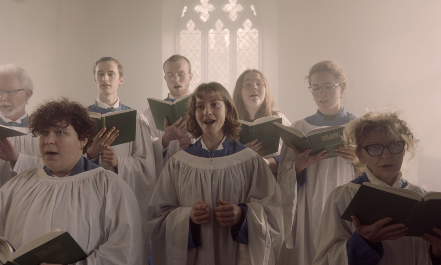 Choir singing in a hazy church wearing robes.