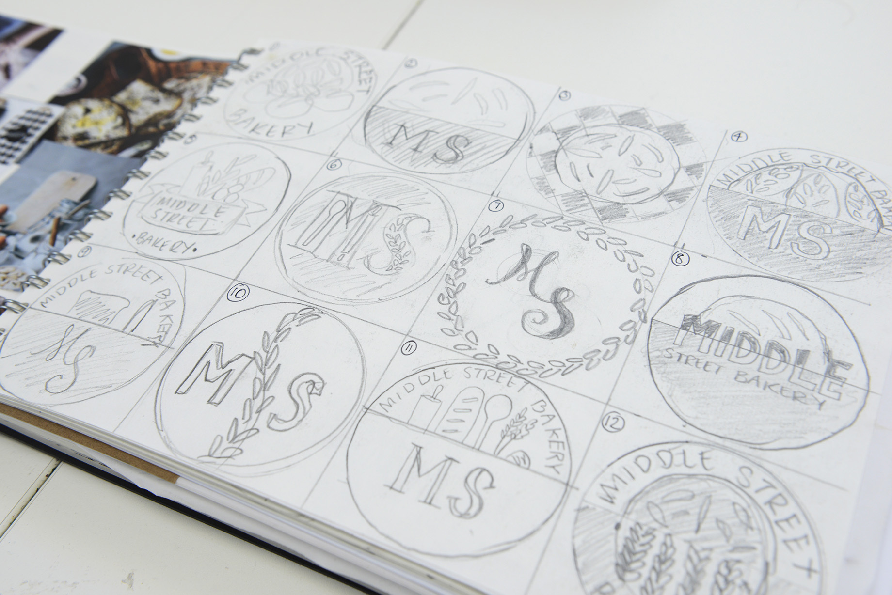 Sketchbook page with 12 different pencil drawings of Middle Street Bakery logos.