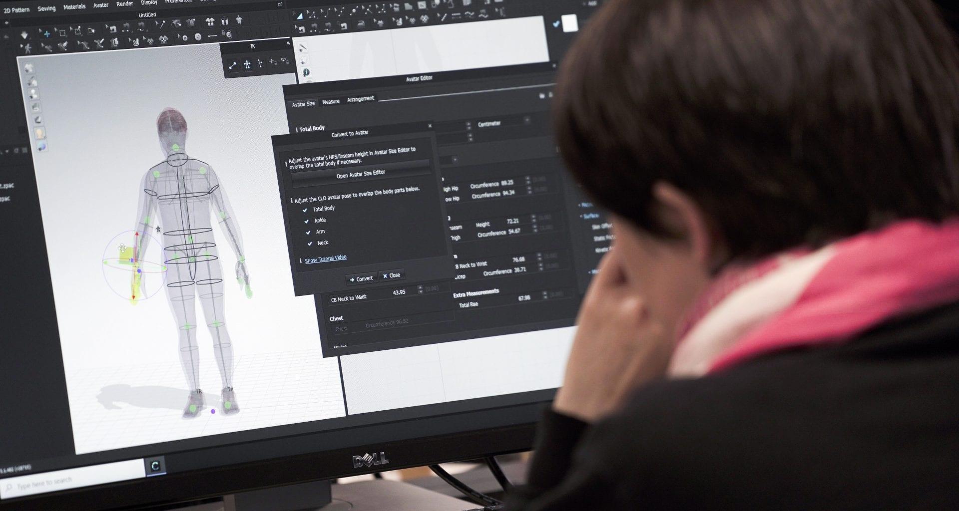 A person works with some design software on a PC.
