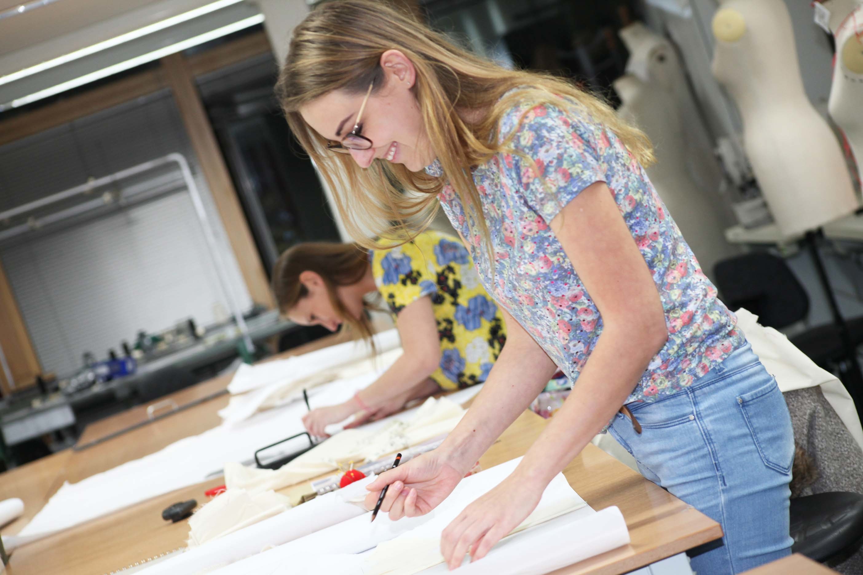 A person stands at a table and prepares to draw on a large piece of paper.