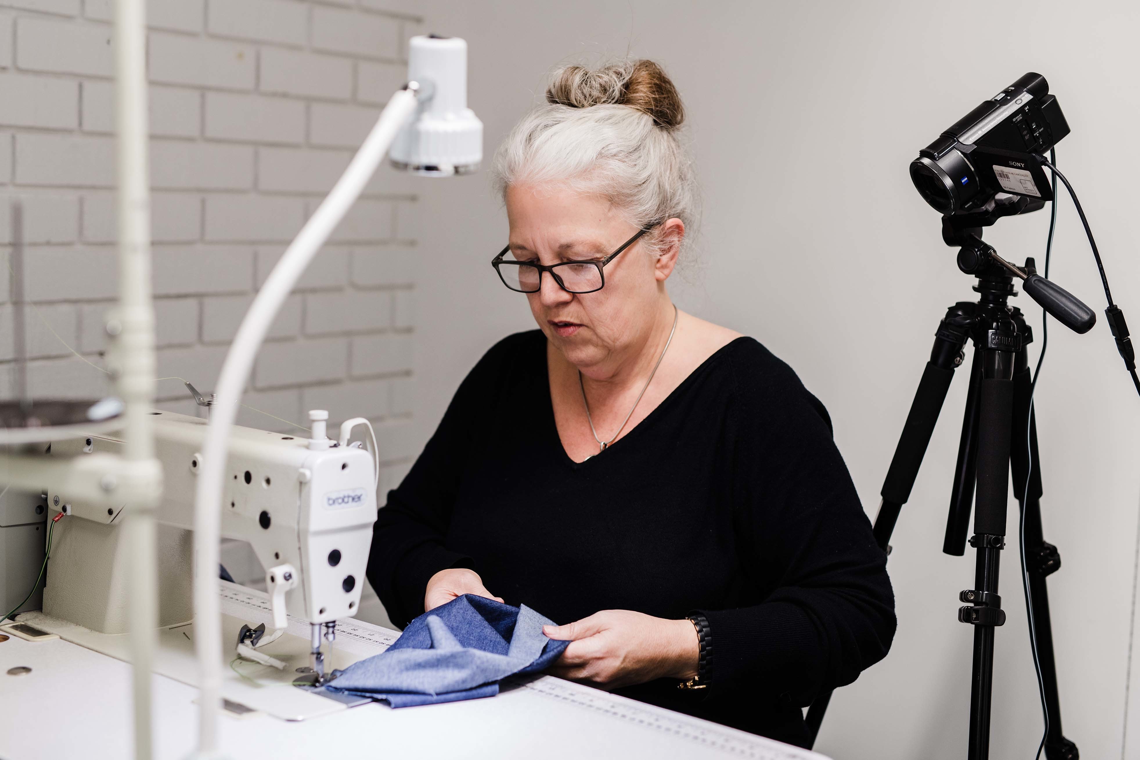 A person sits working and concentrating at a sewing machine.