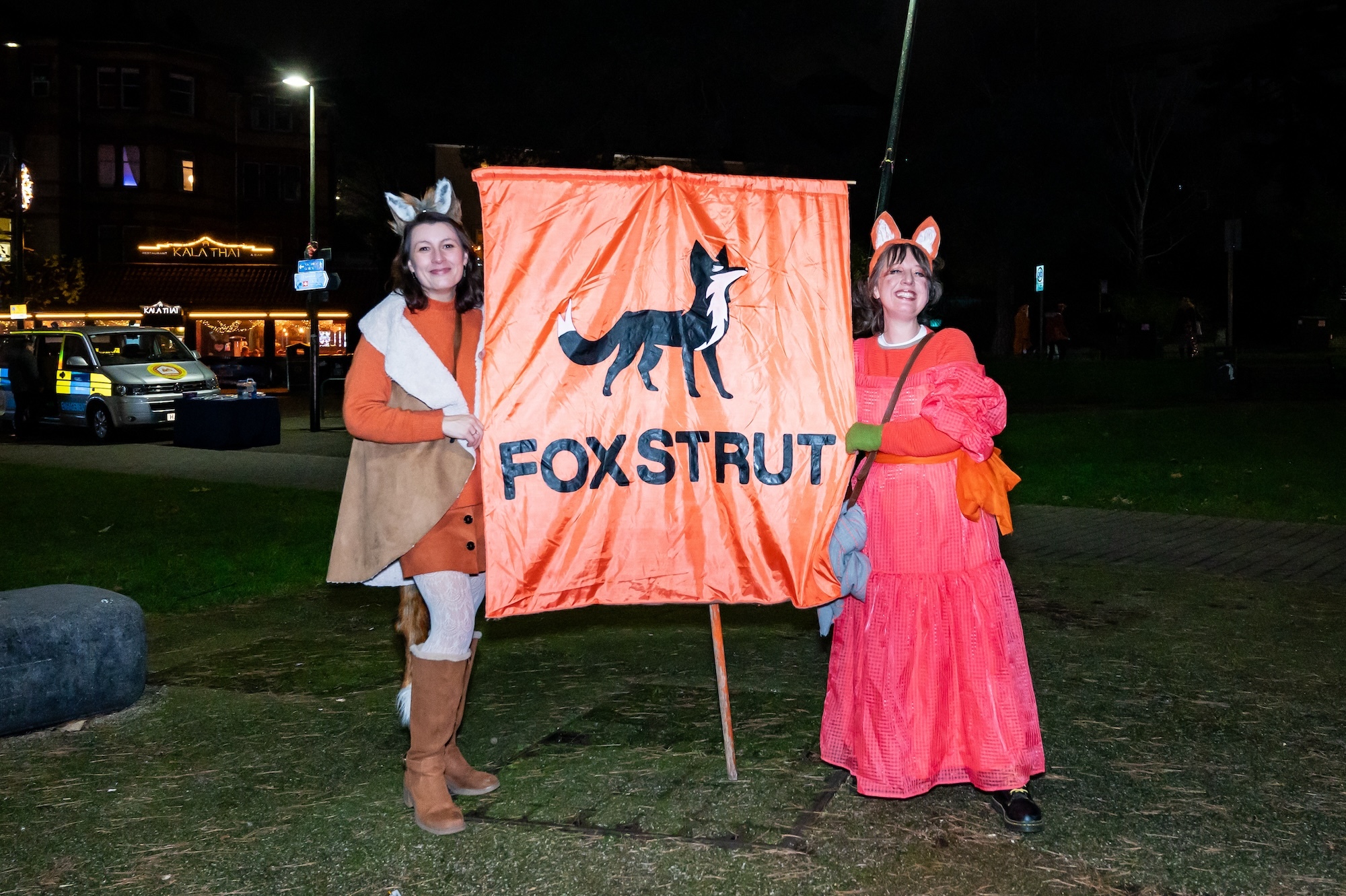 J Jackson and L Rees holding a large orange banner showing a fox and the text reading "FOXSTRUT" underneath.