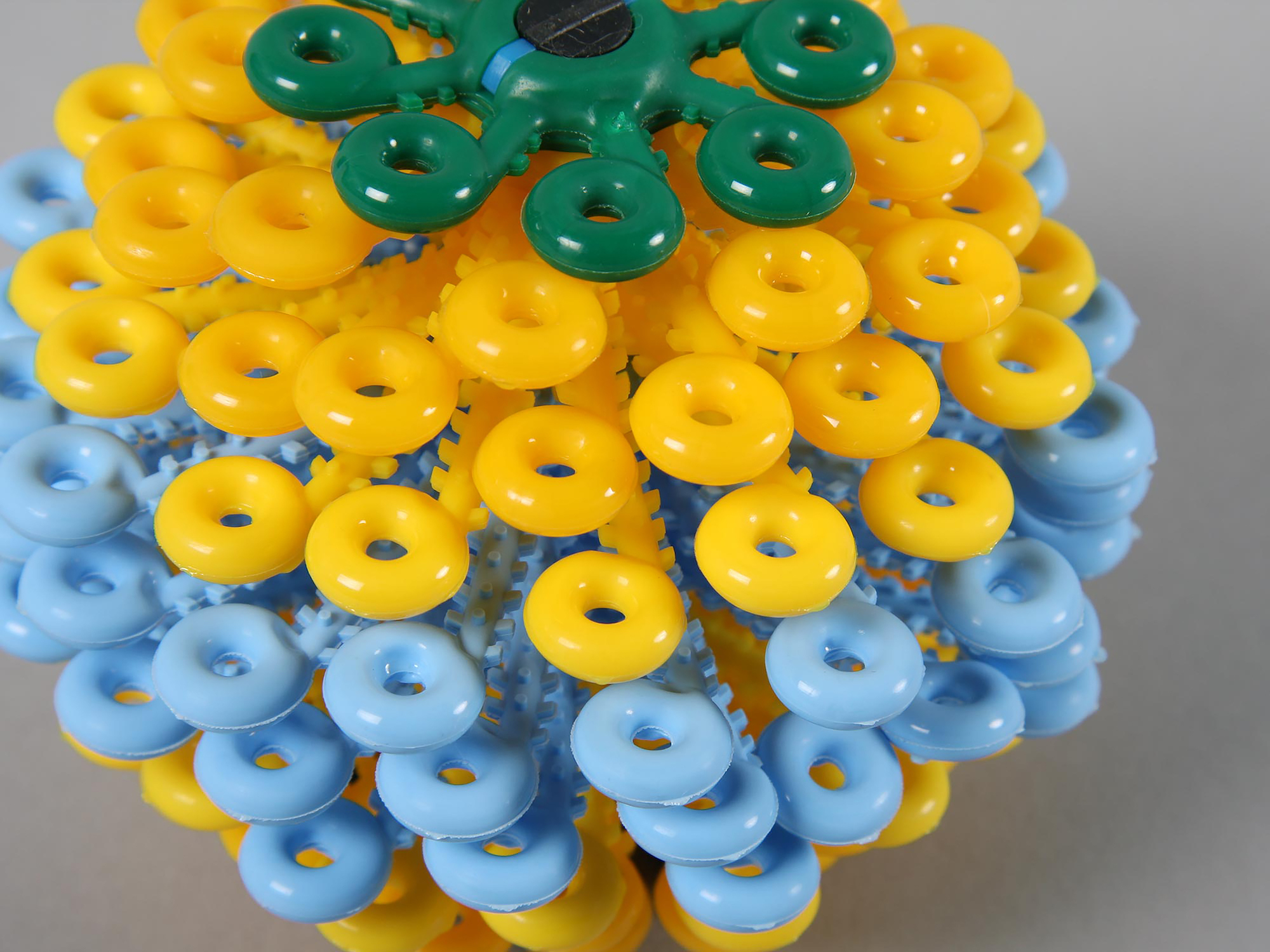 Colourful plastic object made up of stacked wheels with loops on the ends.