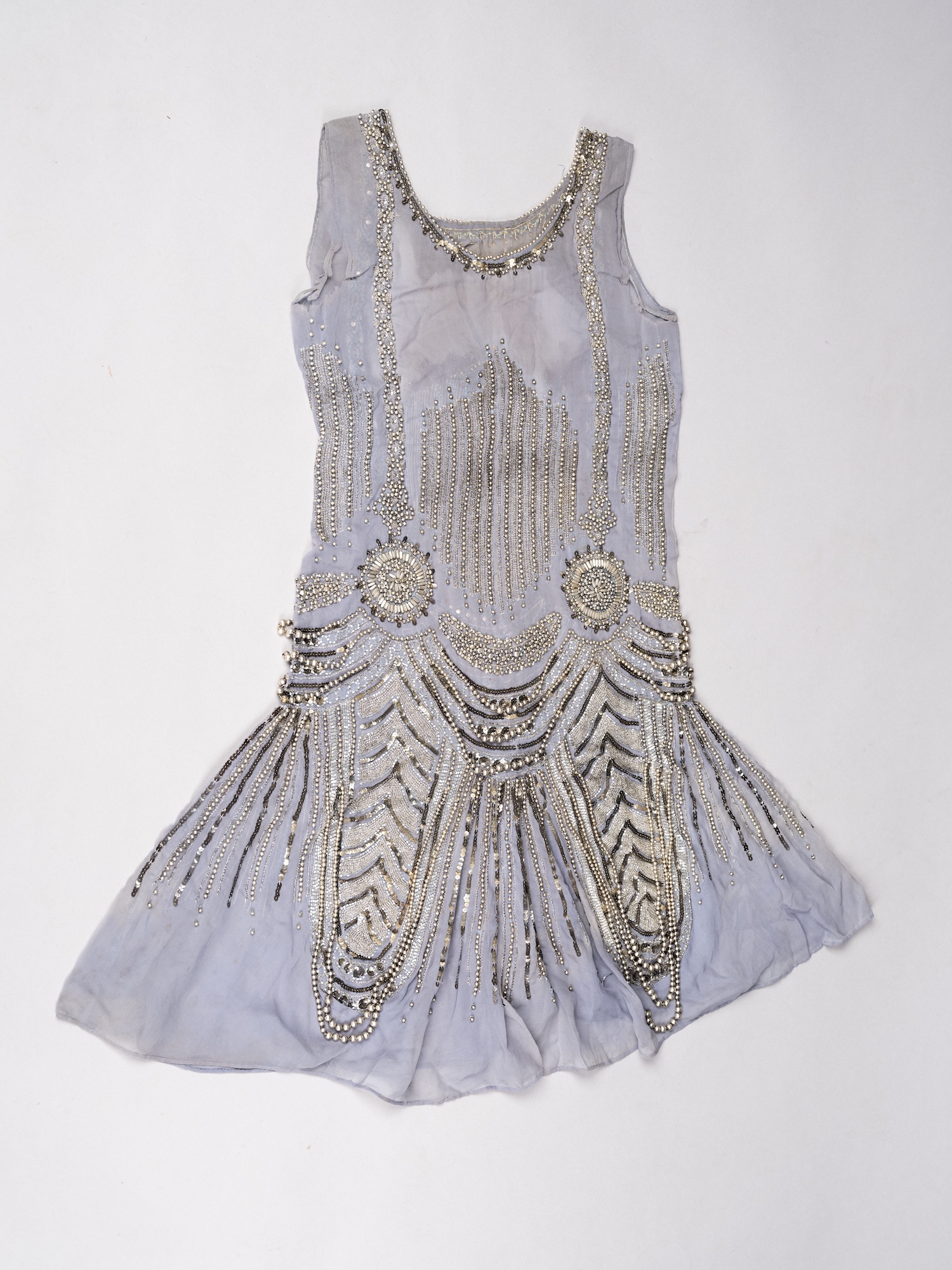 A grey and silver beaded 1920s flapper dress, displayed on a plain white surface.