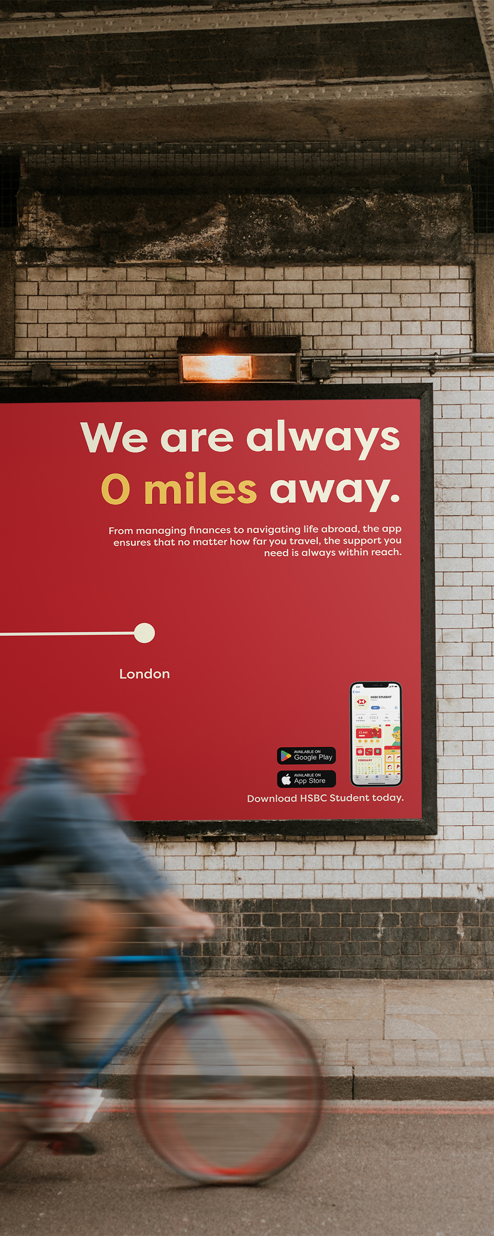 Red HSBC advertisement on white tiled underground station wall with blurred cyclist passing. Text reads "We are always 0 miles away."