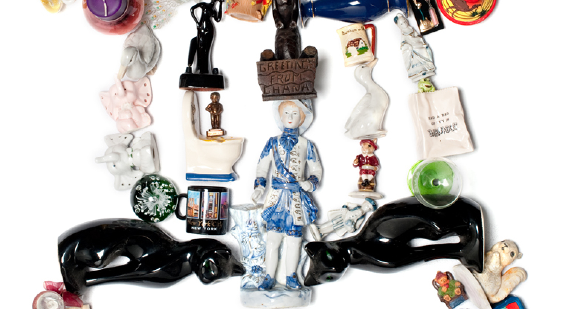 A sculpture made out of various toys and ornaments rests on a plain surface.